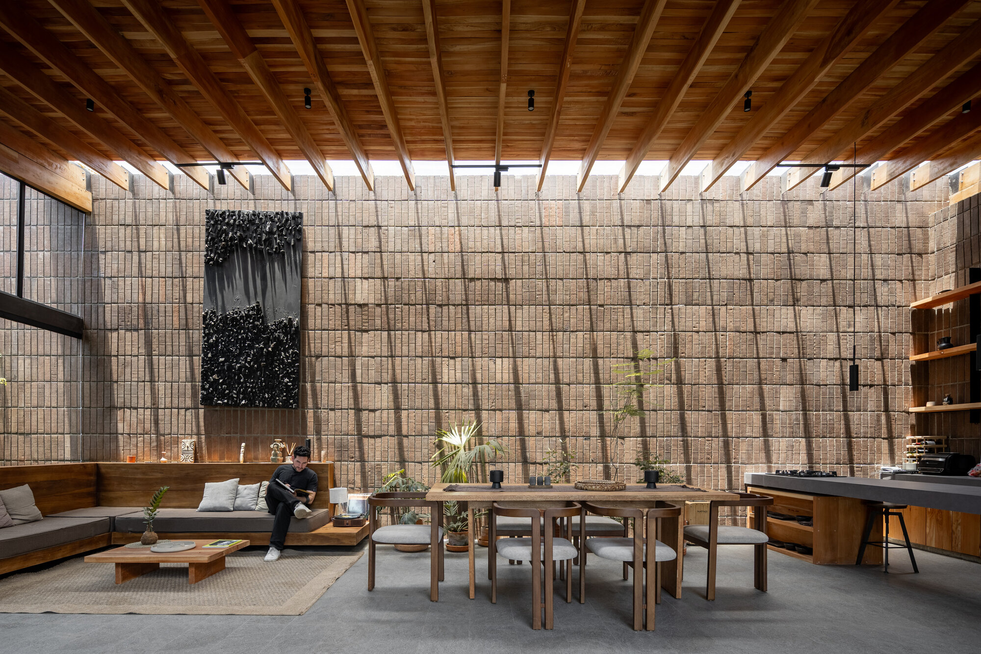 Interior living space with gridded concrete block wall and timber beam ceiling under diffused daylight