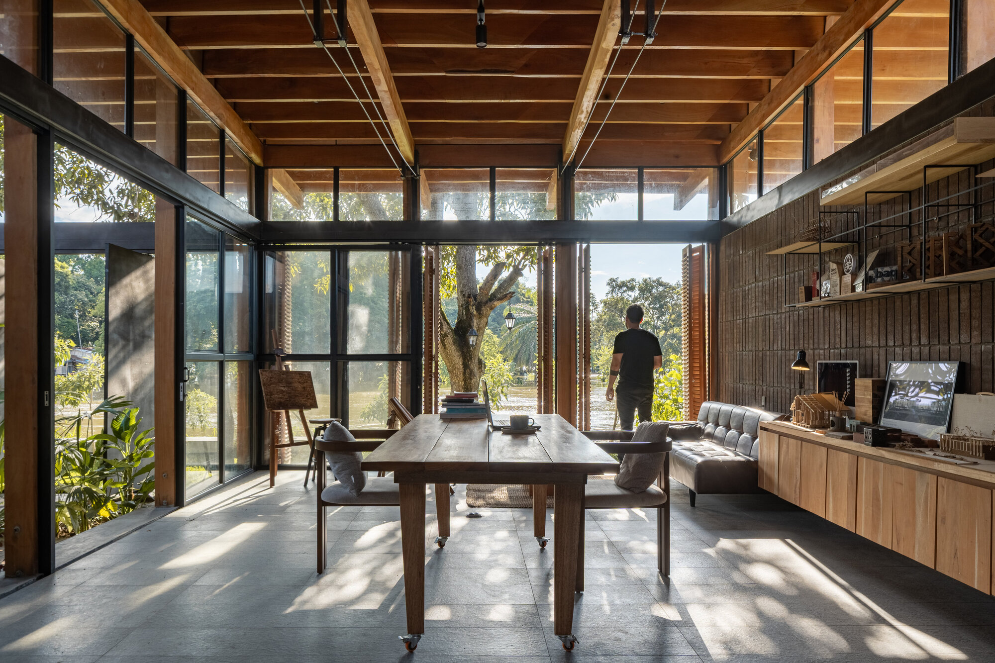 Dining area with timber ceiling and clerestory windows casting diagonal shadows across the concrete floor
