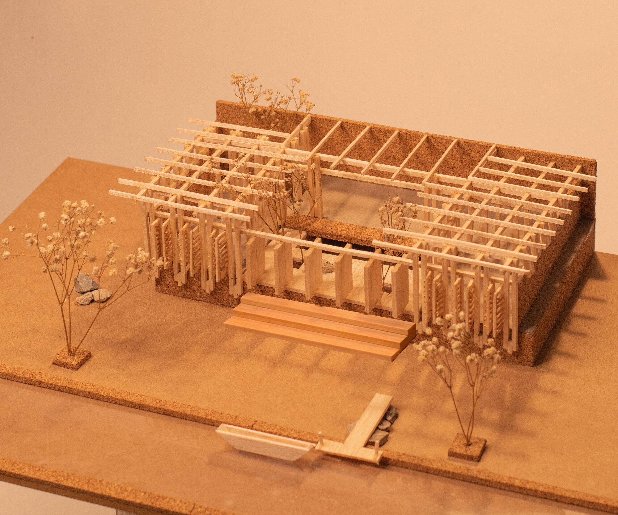 Physical model with exposed timber grid structure and planted courtyard under warm exhibition lighting
