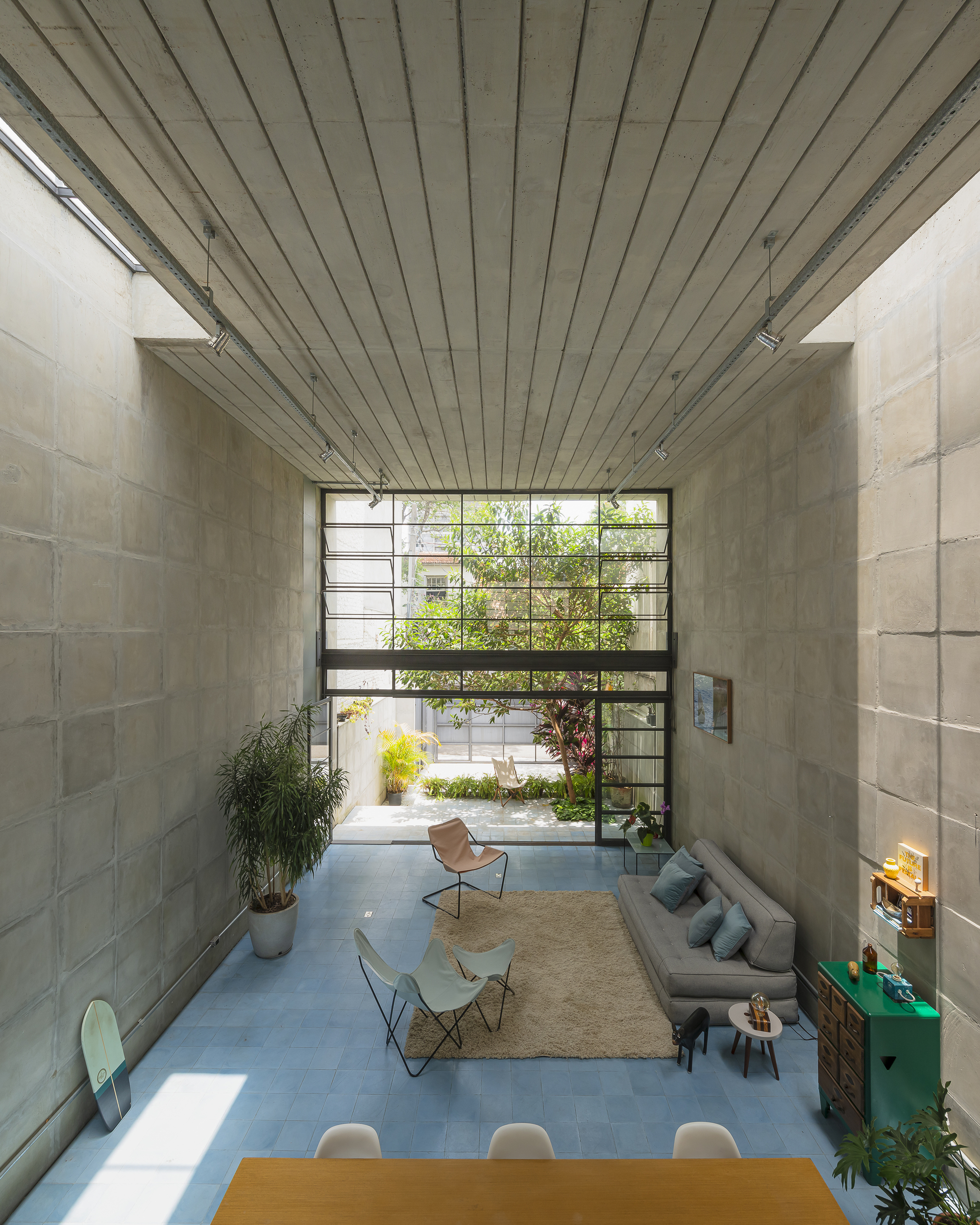View through double-height space toward steel-framed window wall with courtyard garden beyond