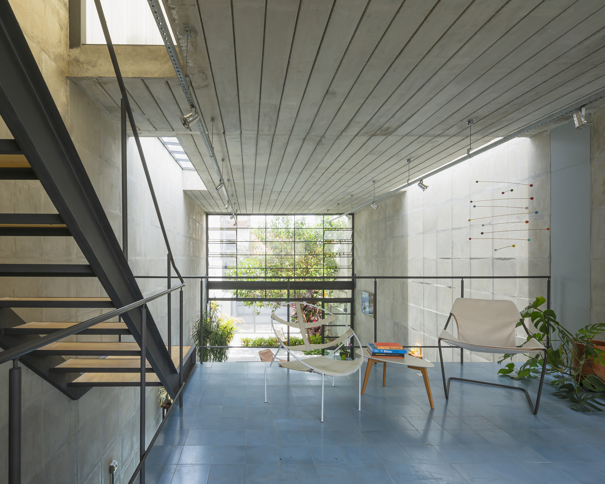 Steel staircase with cable railing ascending beside concrete block wall and clerestory window
