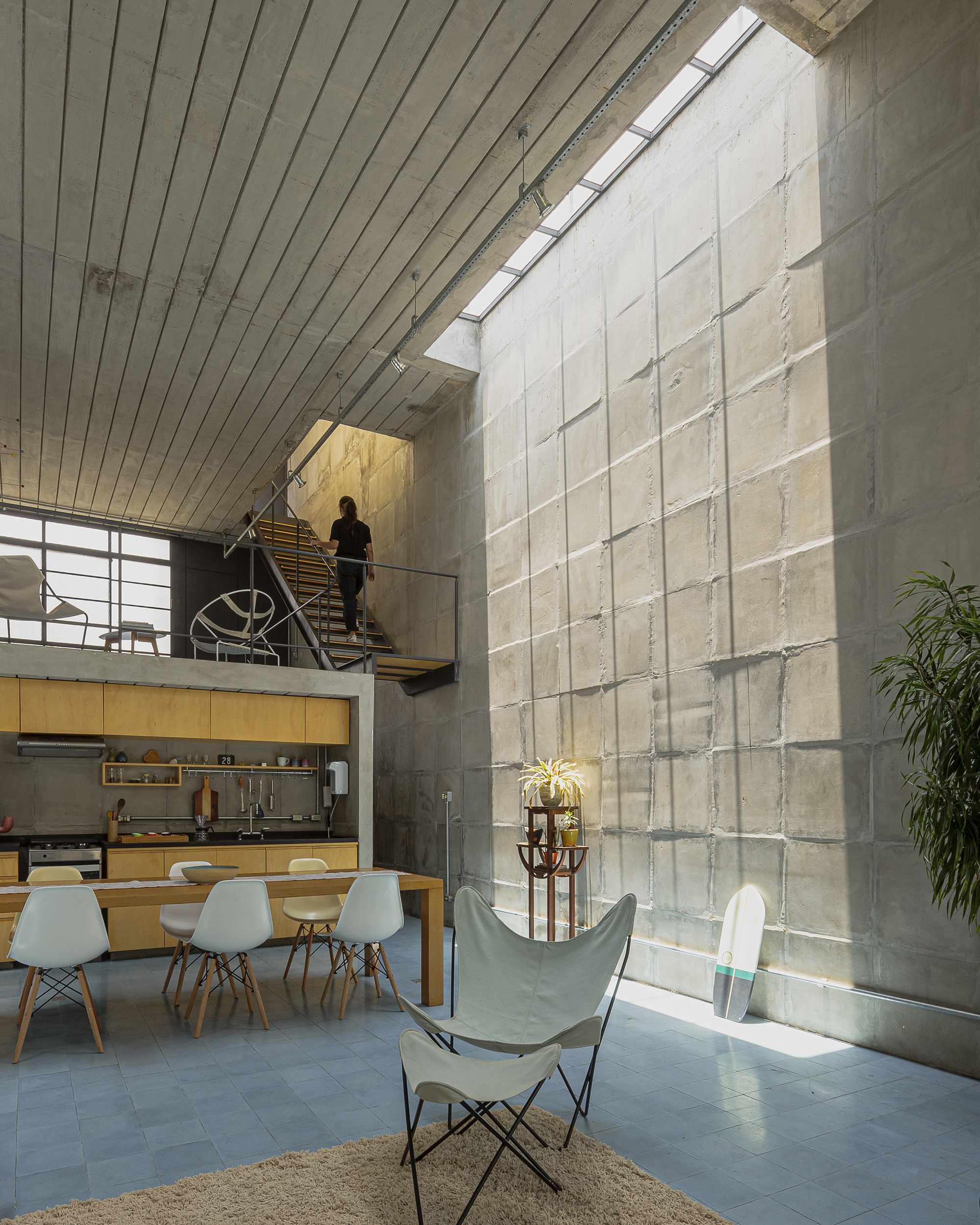 Double-height concrete block wall with figure descending timber stair on mezzanine level