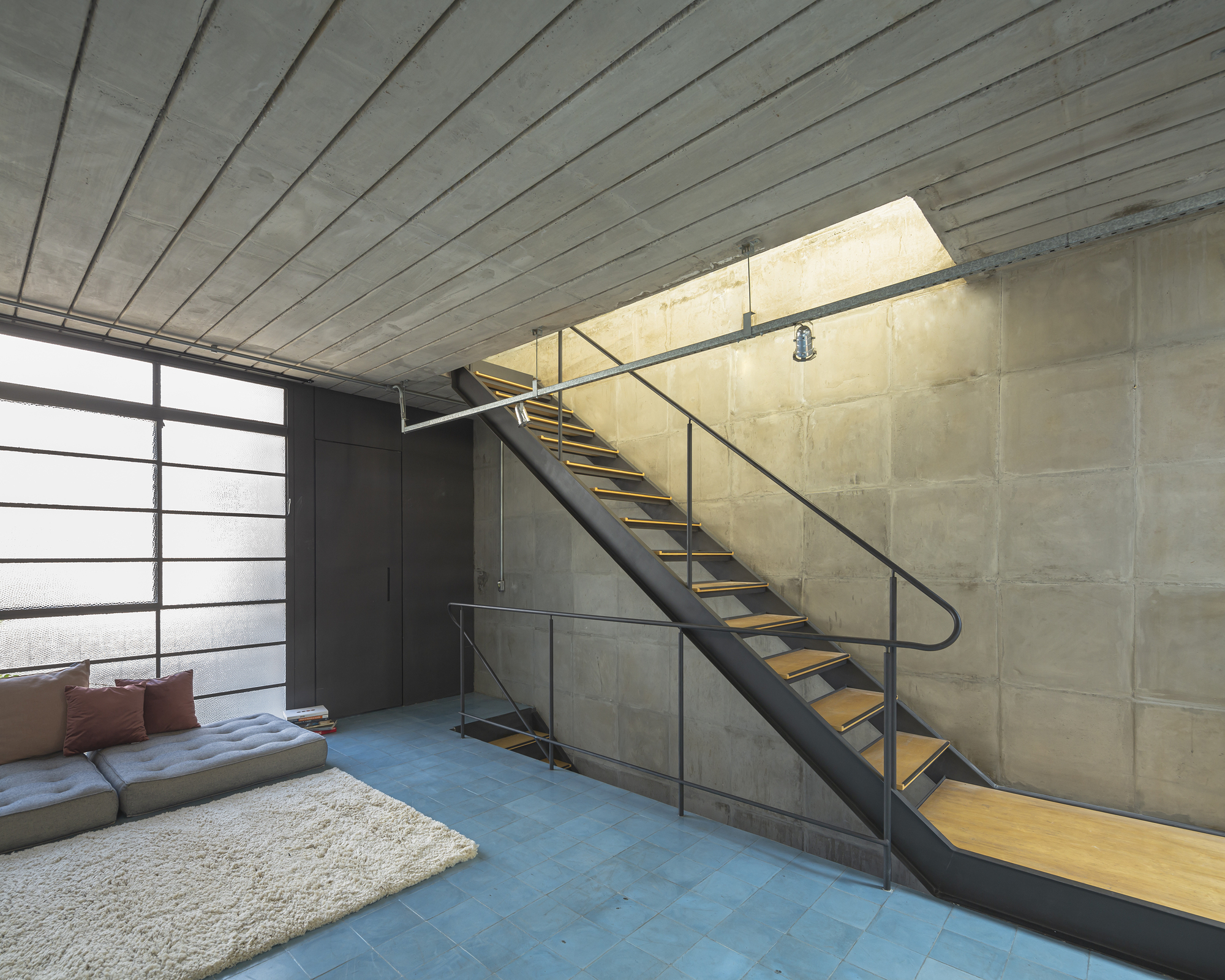 Interior view of metal staircase with wood treads ascending along exposed concrete block wall
