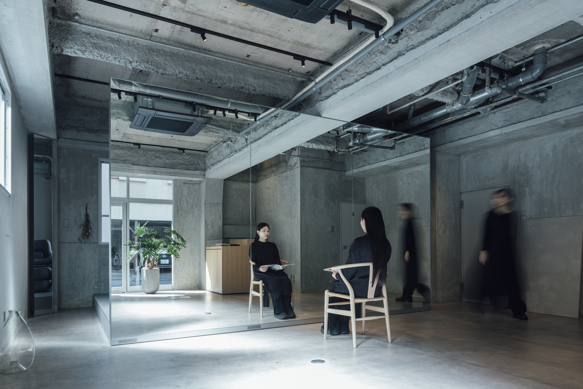 Interior space with glass partition and concrete walls as people in motion pass through the corridor