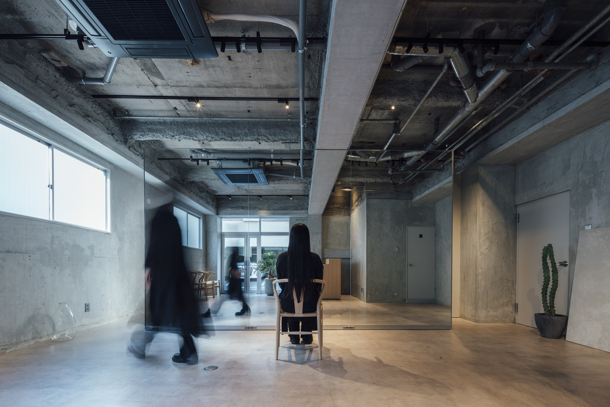 Open floor plan with exposed concrete structure and mechanical systems visible overhead in afternoon light