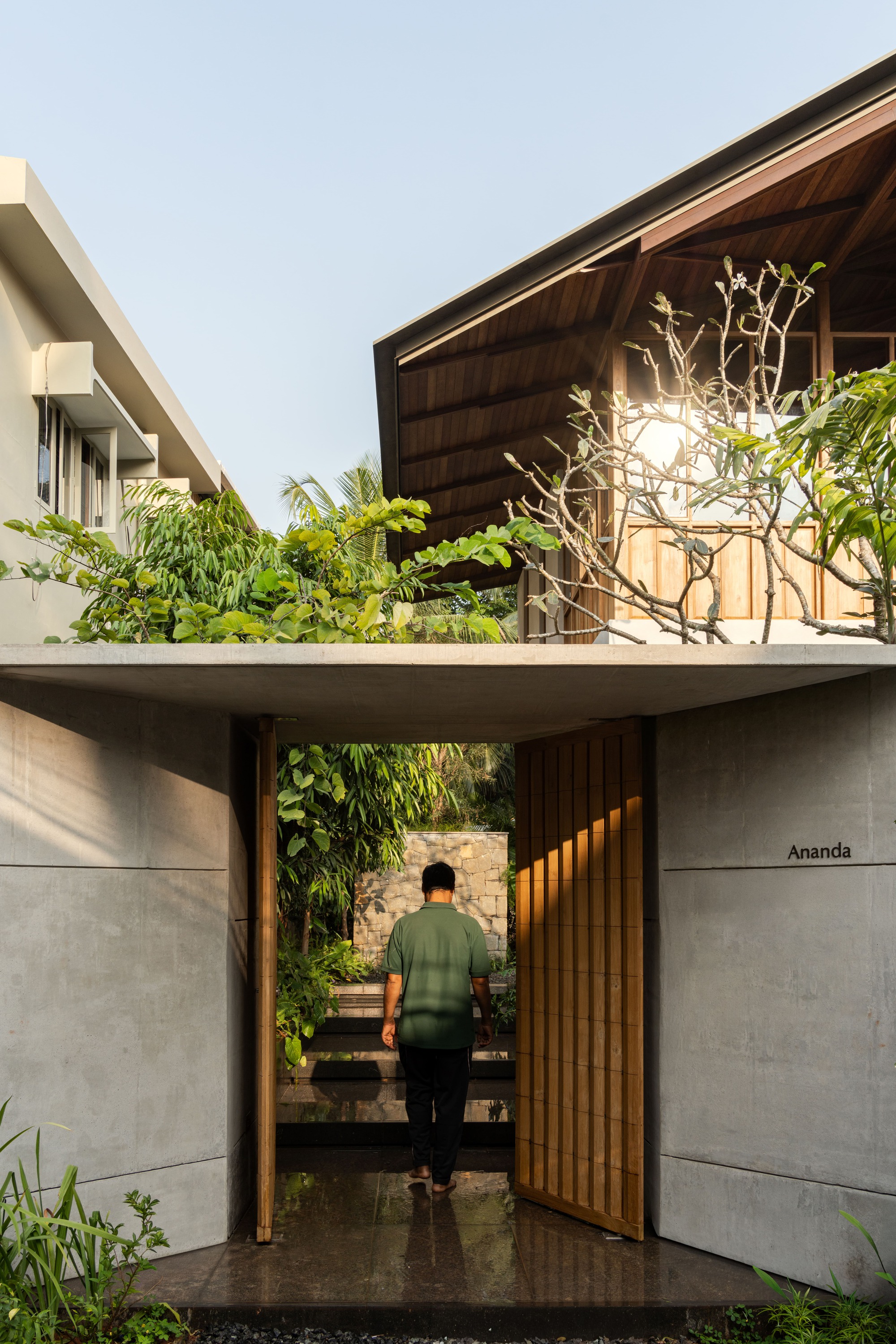 Entry threshold with timber-lined gateway and person walking toward interior courtyard staircase