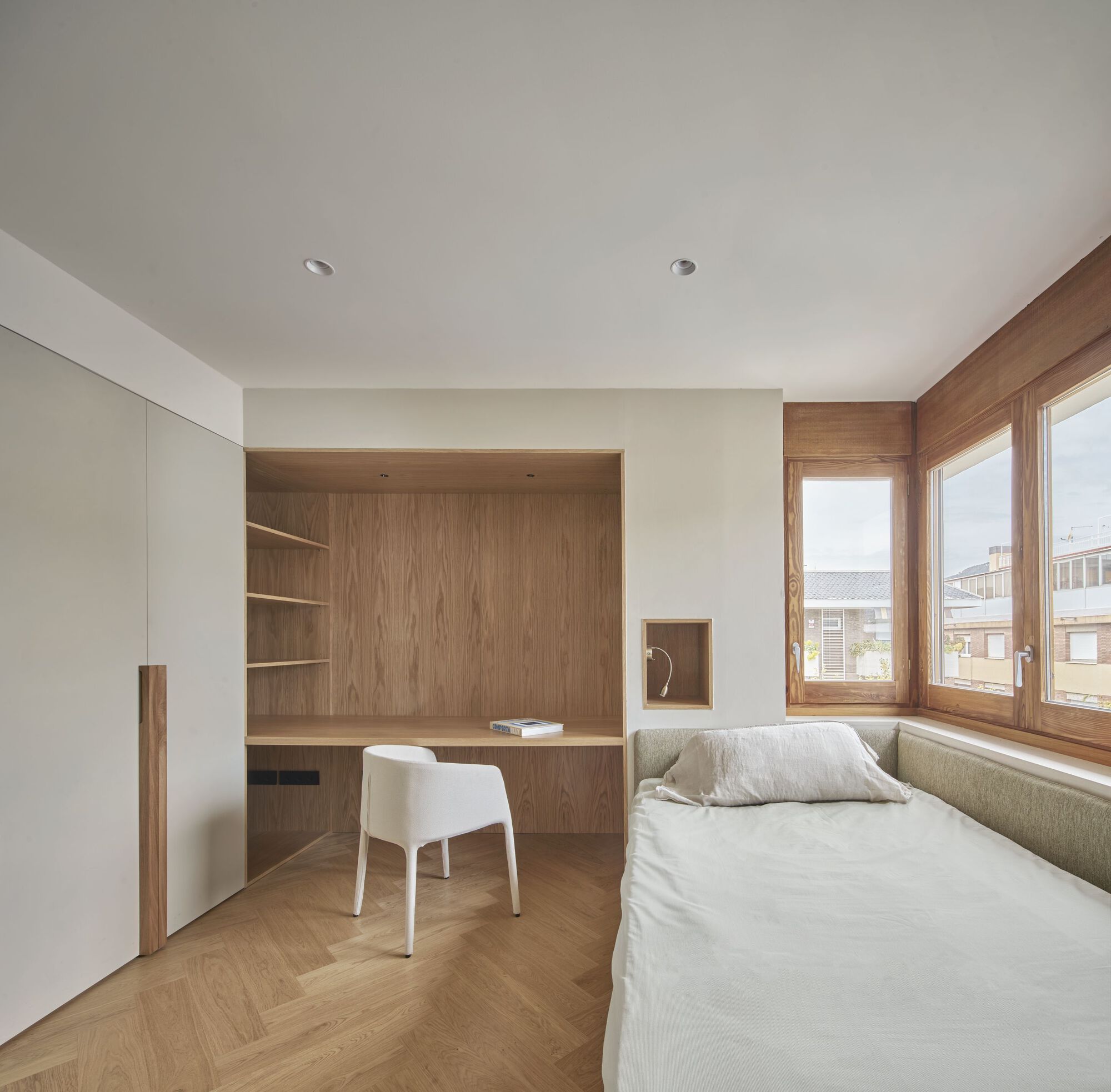 Bedroom with built-in oak desk alcove, upholstered window seat, and timber casement windows