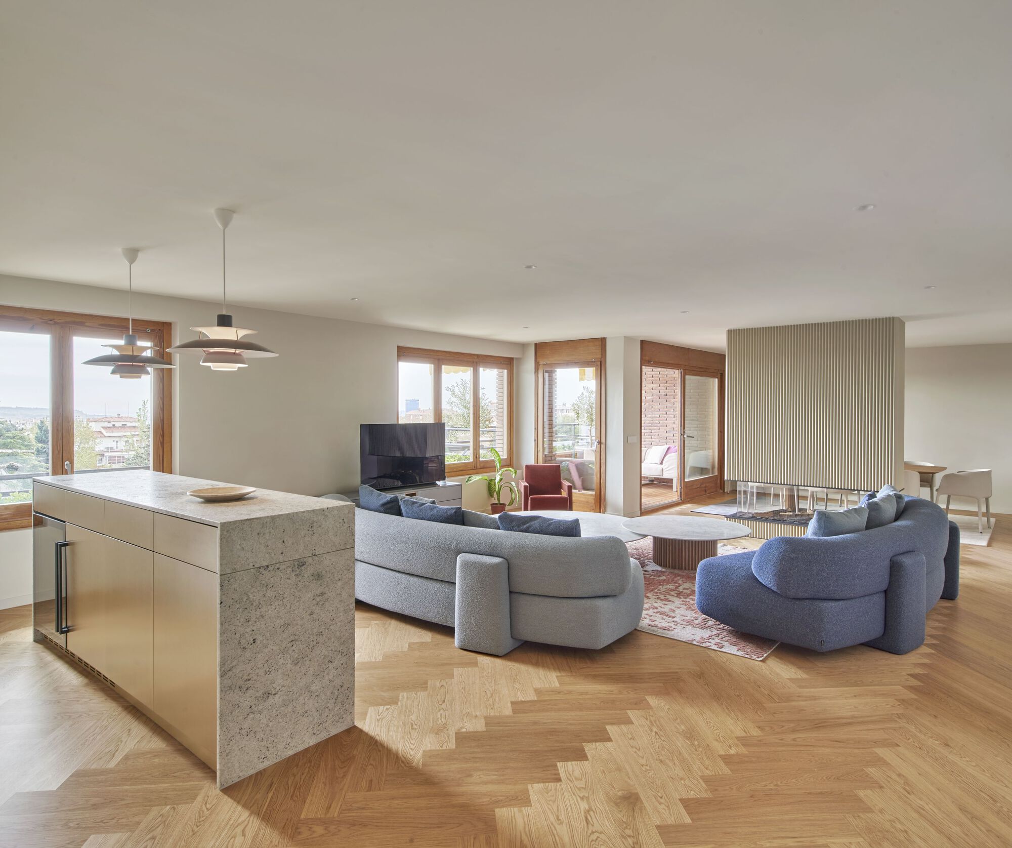 Open living area with terrazzo kitchen island and timber-framed windows overlooking the city