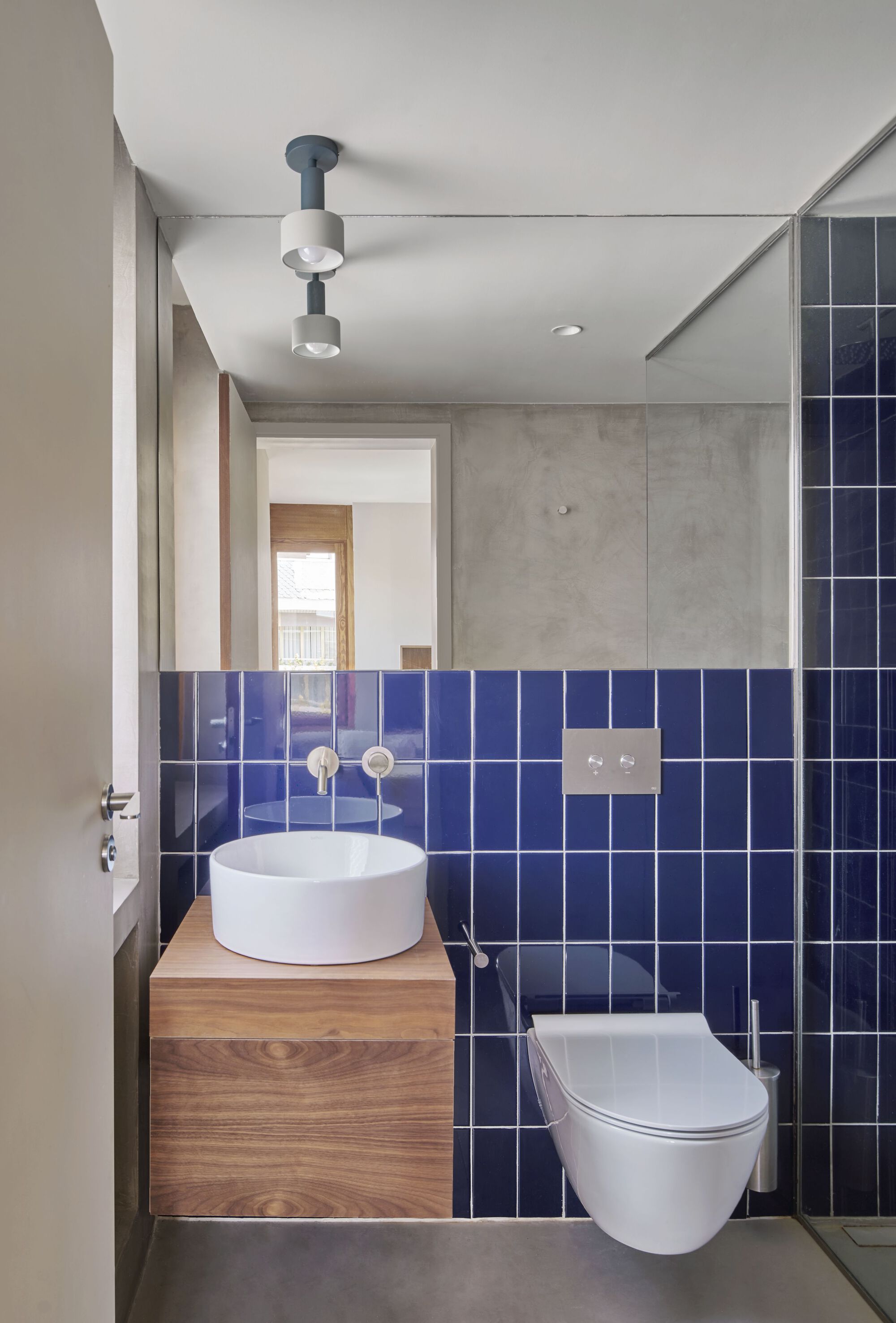 Compact bathroom with cobalt blue square tiles and a round vessel sink on timber vanity