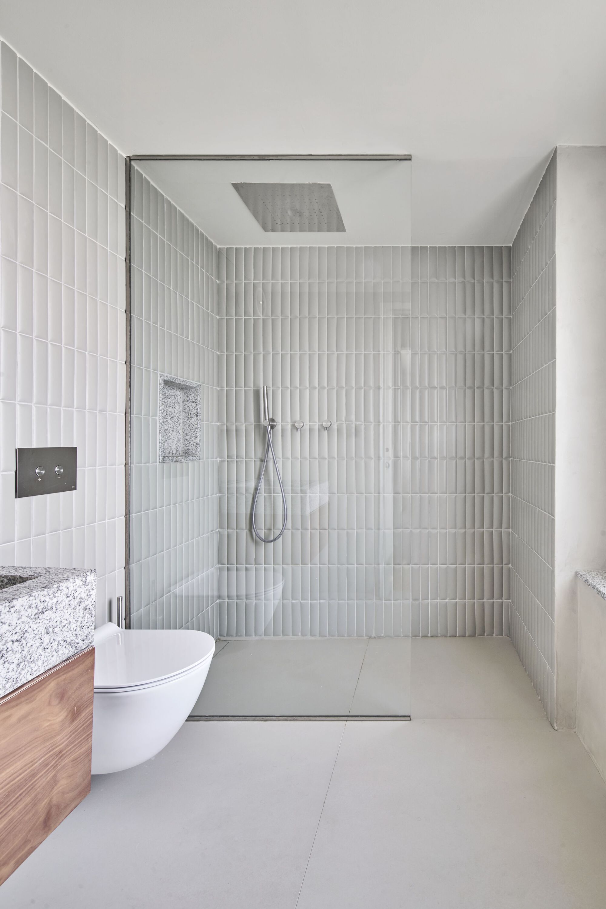 Glass-enclosed shower with vertical white tile walls and ceiling-mounted rainfall showerhead