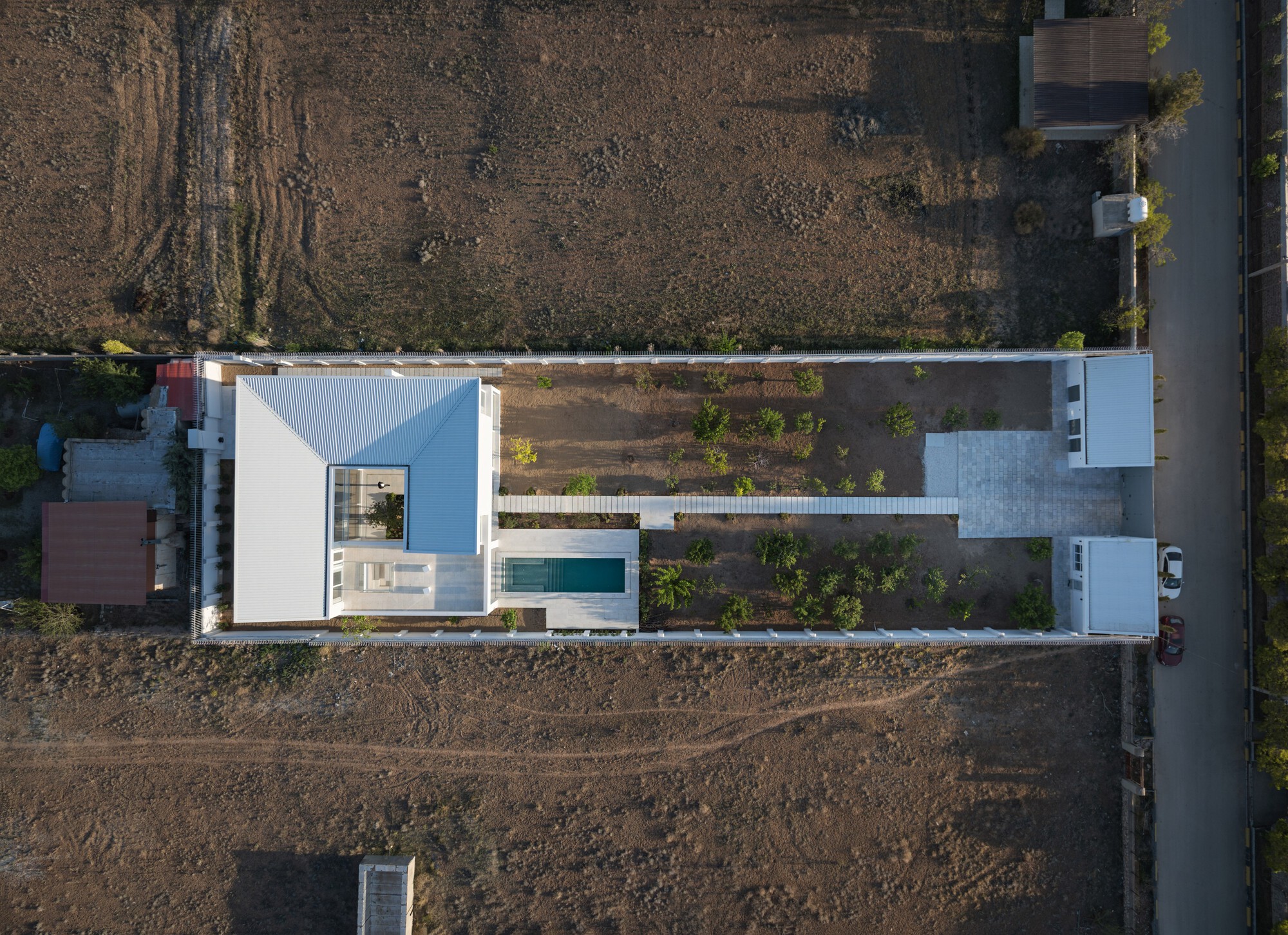 Aerial view of the white volumes arranged around a central courtyard with pool and terraced garden beds