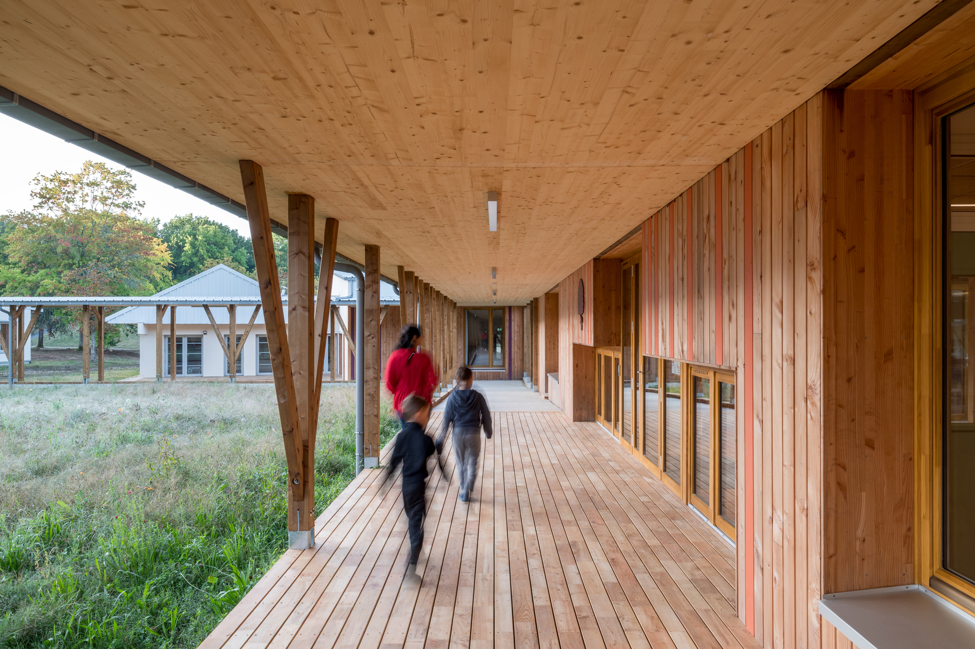 Covered timber walkway with diagonal wood braces and two children running on the decking