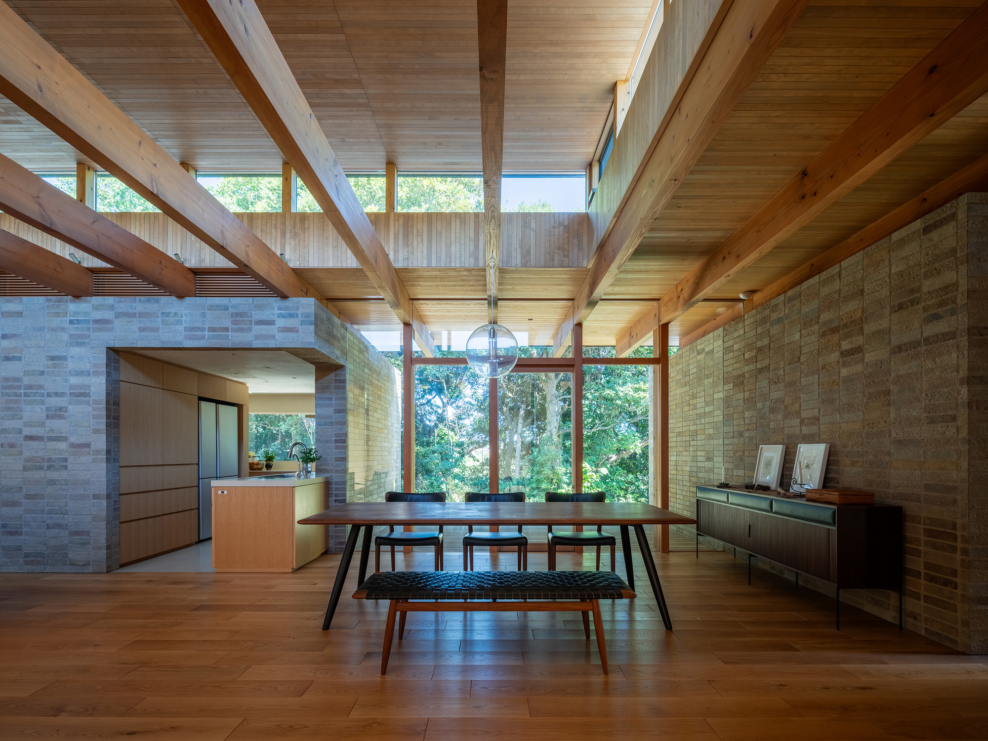 Dining room with exposed timber ceiling structure and clerestory windows overlooking garden
