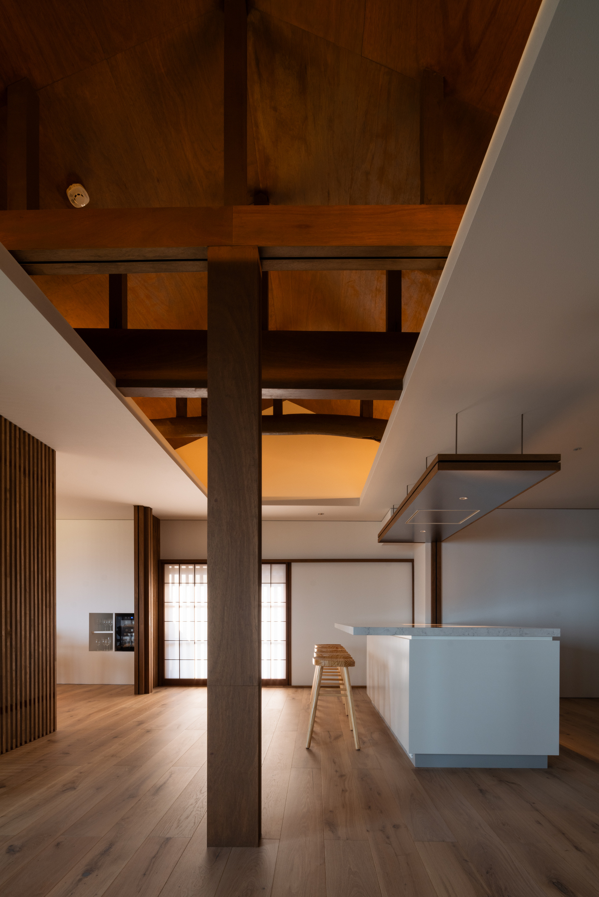 Kitchen island beneath timber post-and-beam structure with translucent sliding screens in the background
