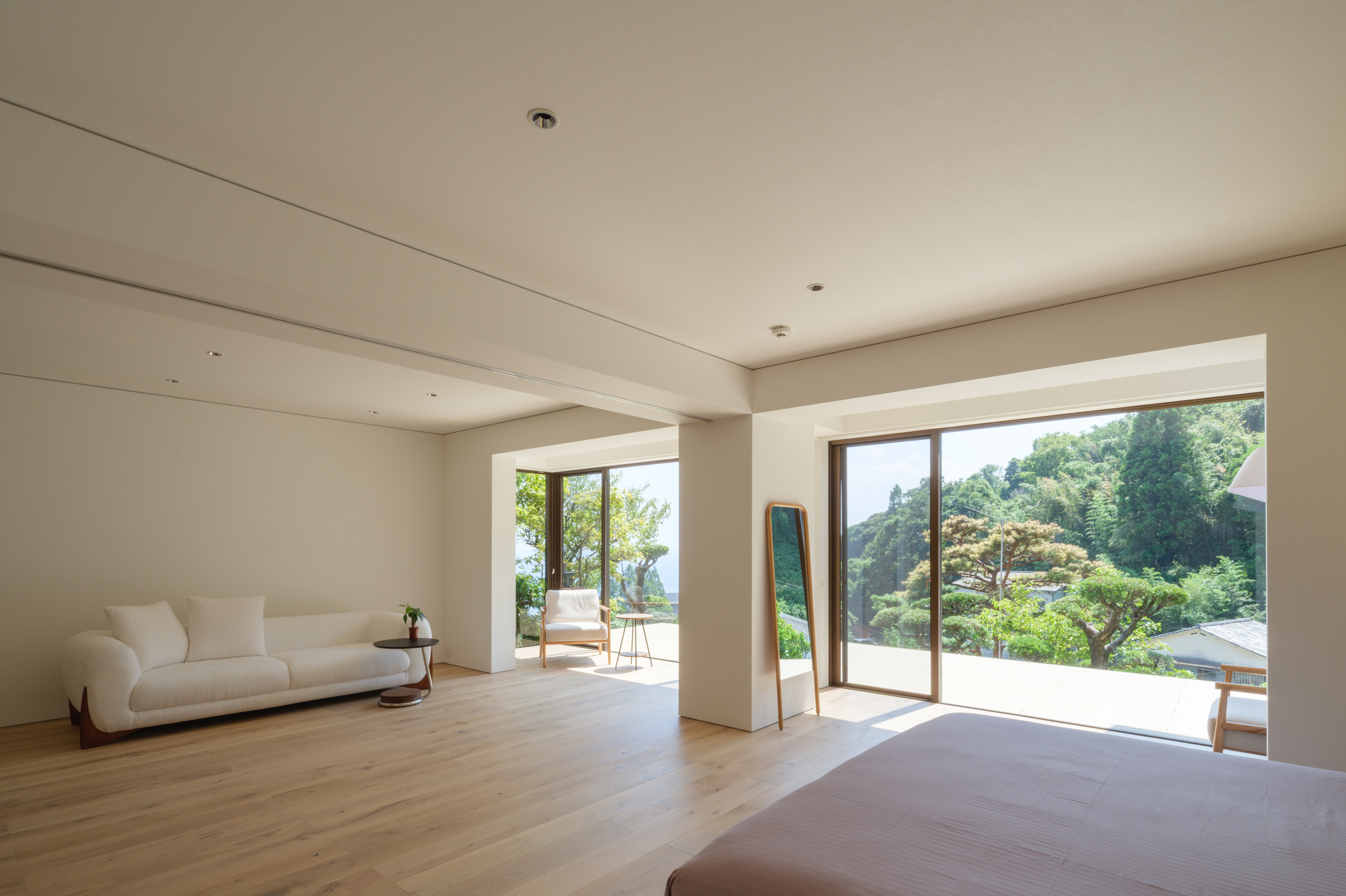 Living room with pale timber flooring and sliding glass doors opening to a sunlit terrace