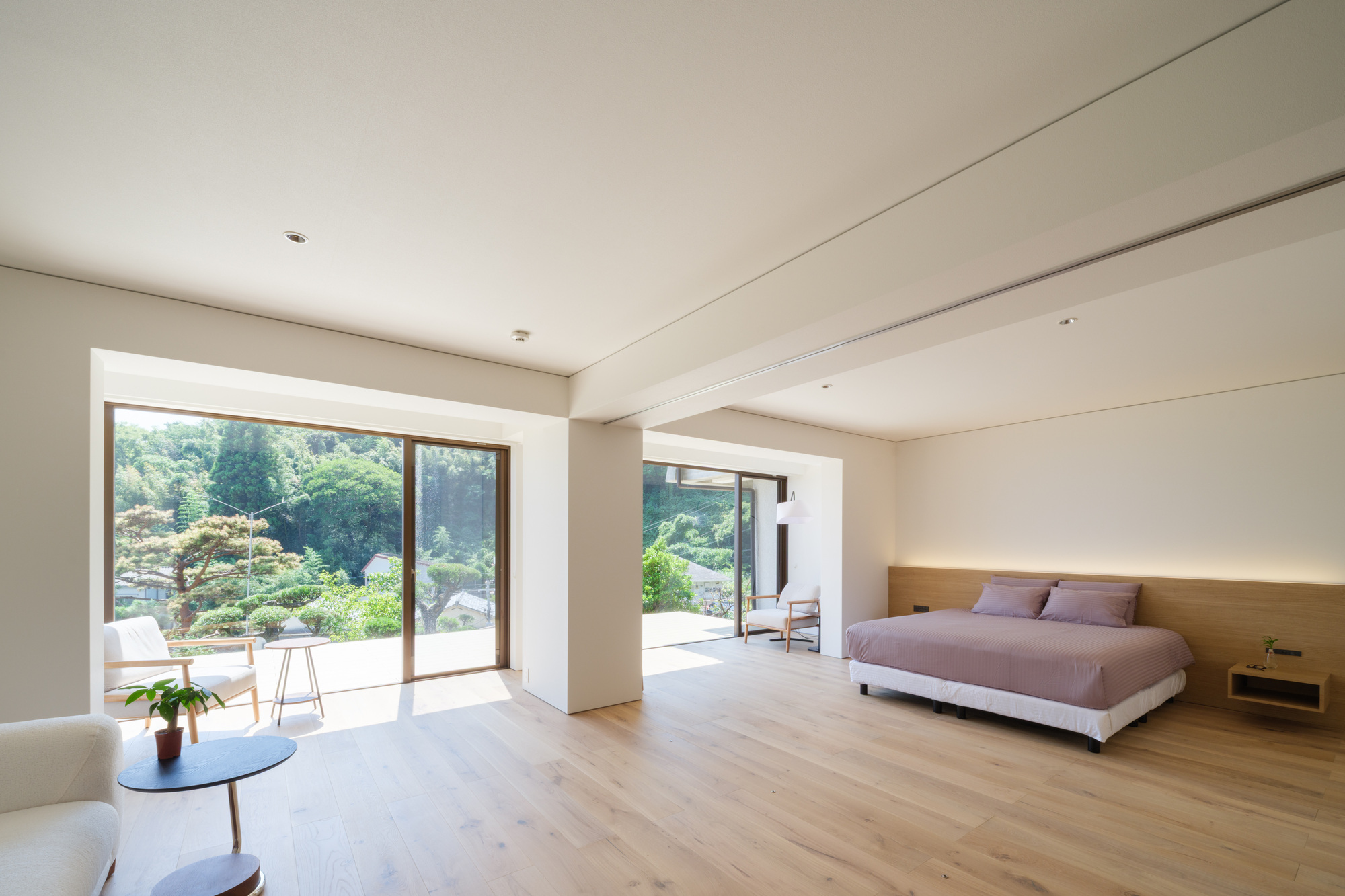 Bedroom with timber headboard wall and glass doors framing views of a sculptural garden and terrace