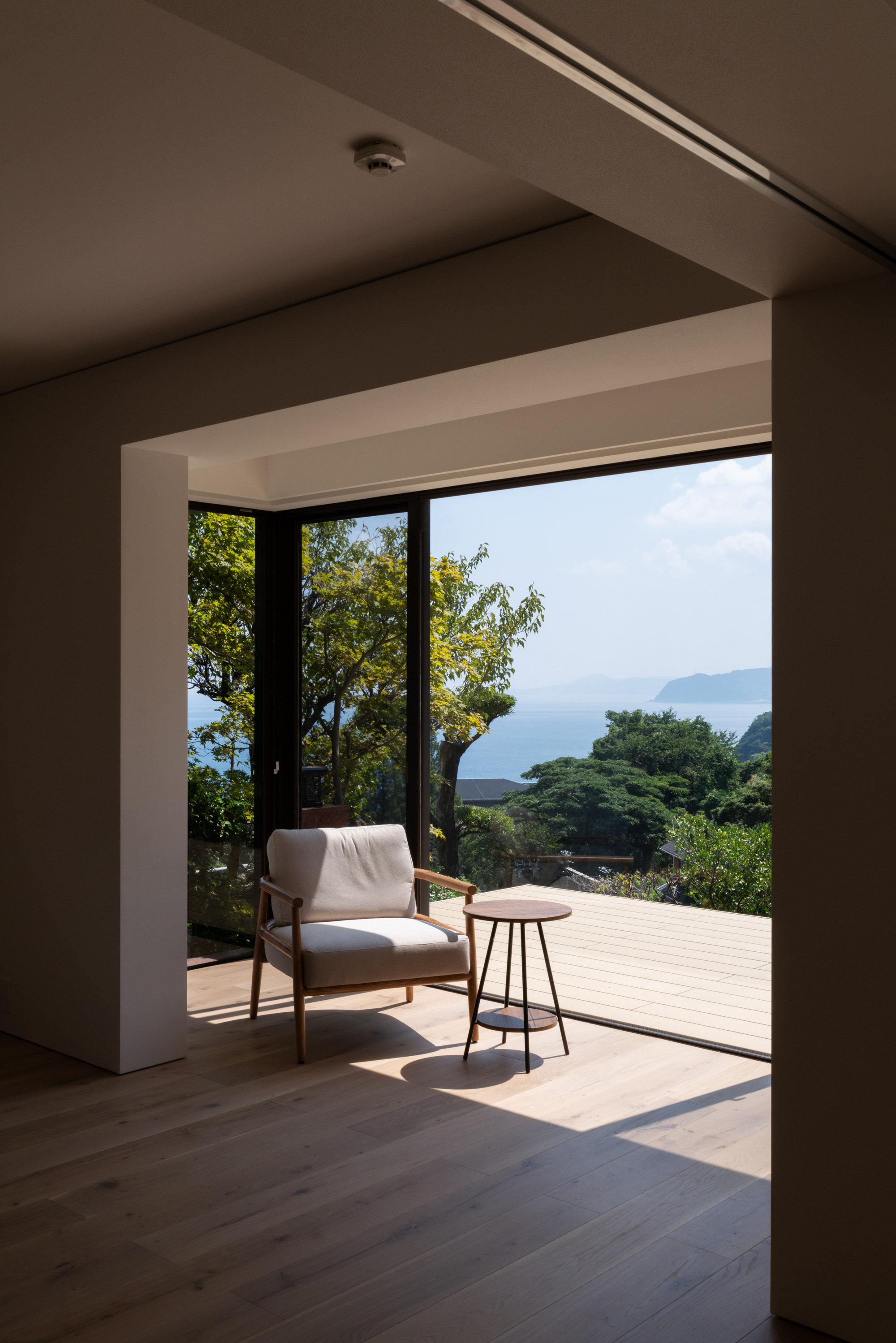 Framed opening from interior room to terrace deck overlooking lush hillside and distant ocean