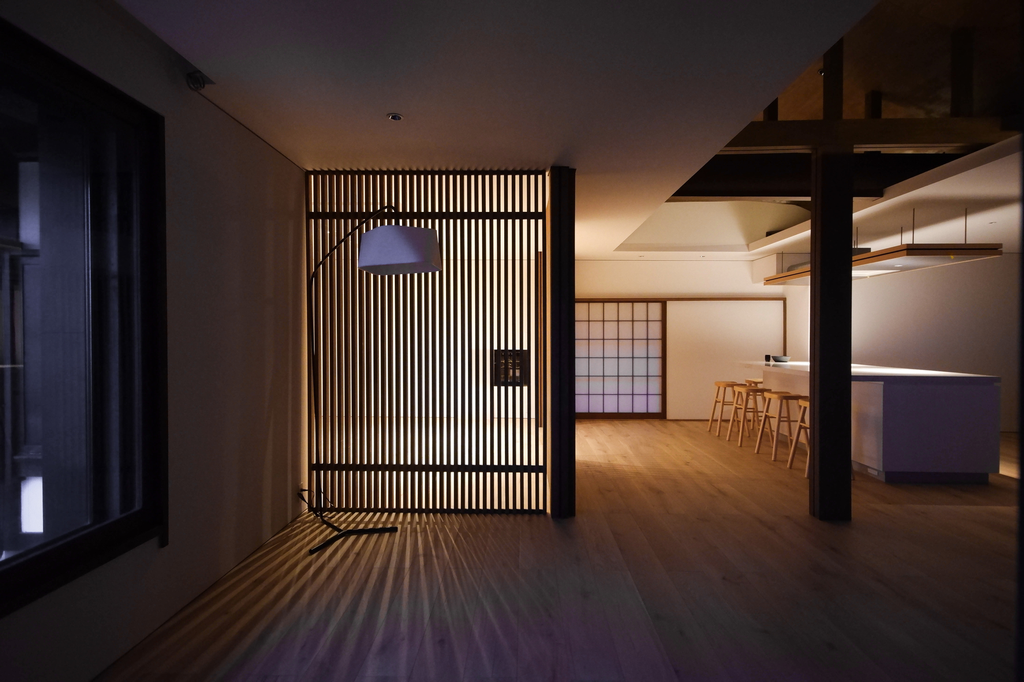 Vertical timber slat screen with backlit striping casting shadow patterns across the floor at dusk