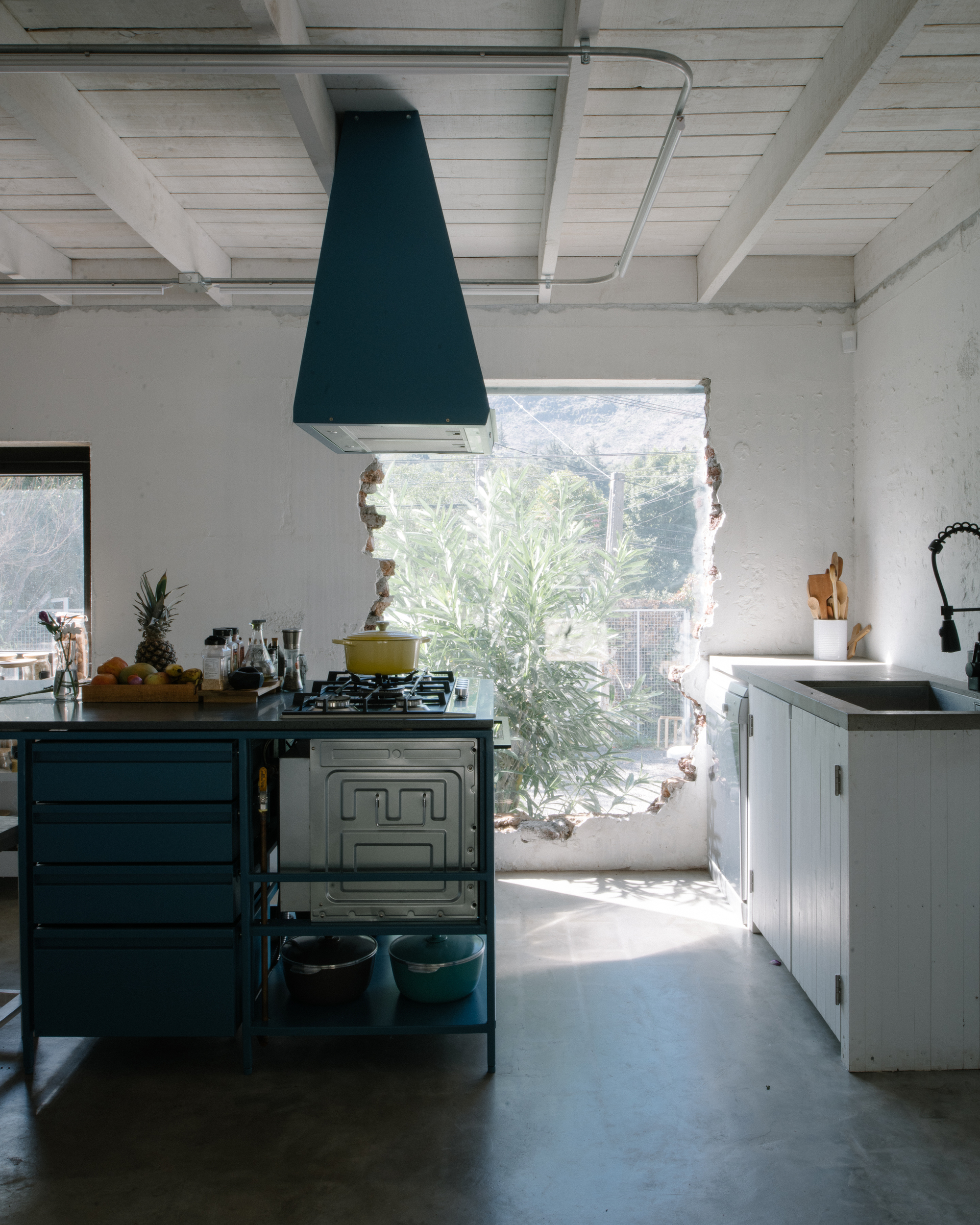 Kitchen with dark blue hood and range framed by a wide window opening