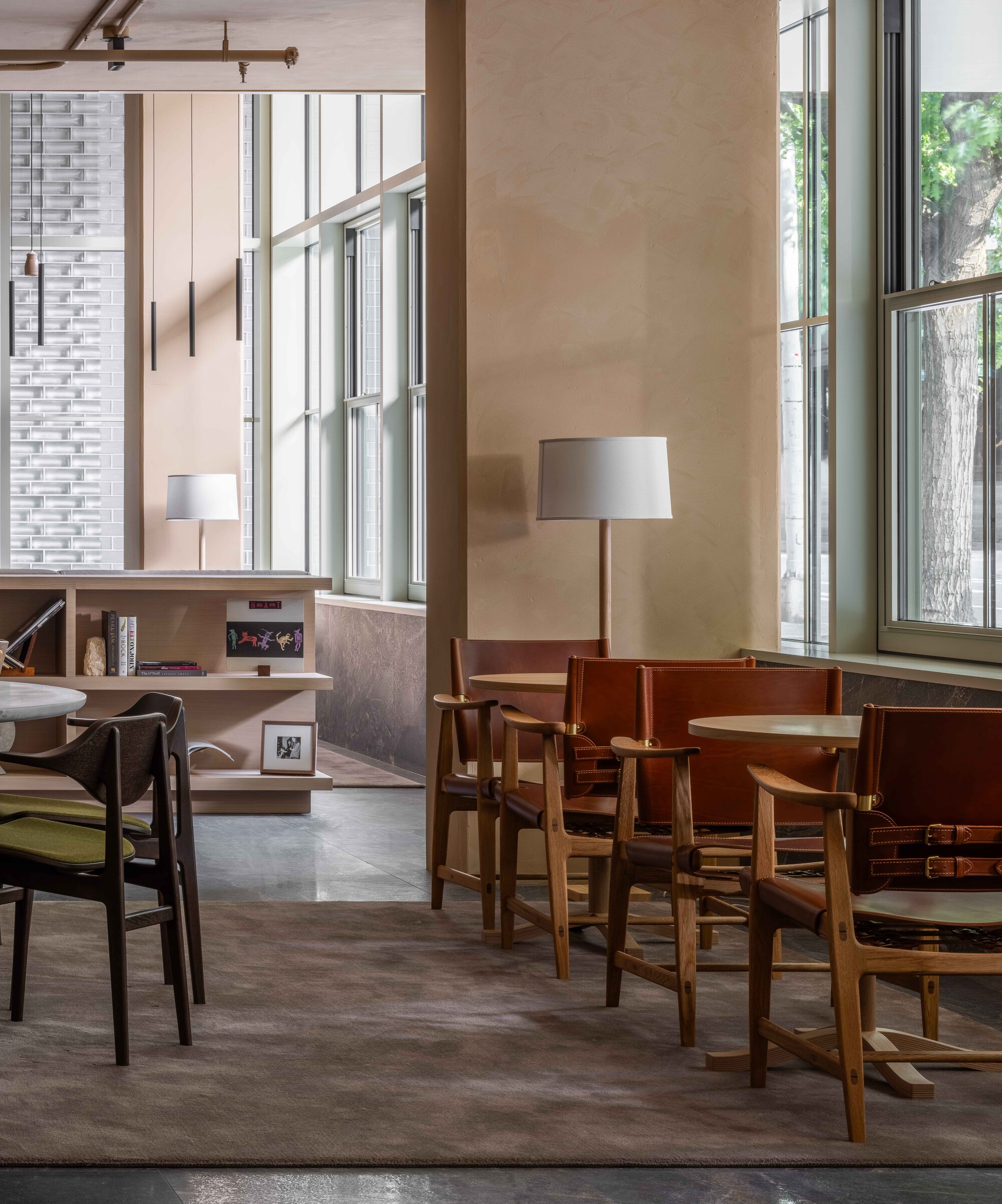 Lobby seating area with timber furniture beneath tall windows in afternoon light