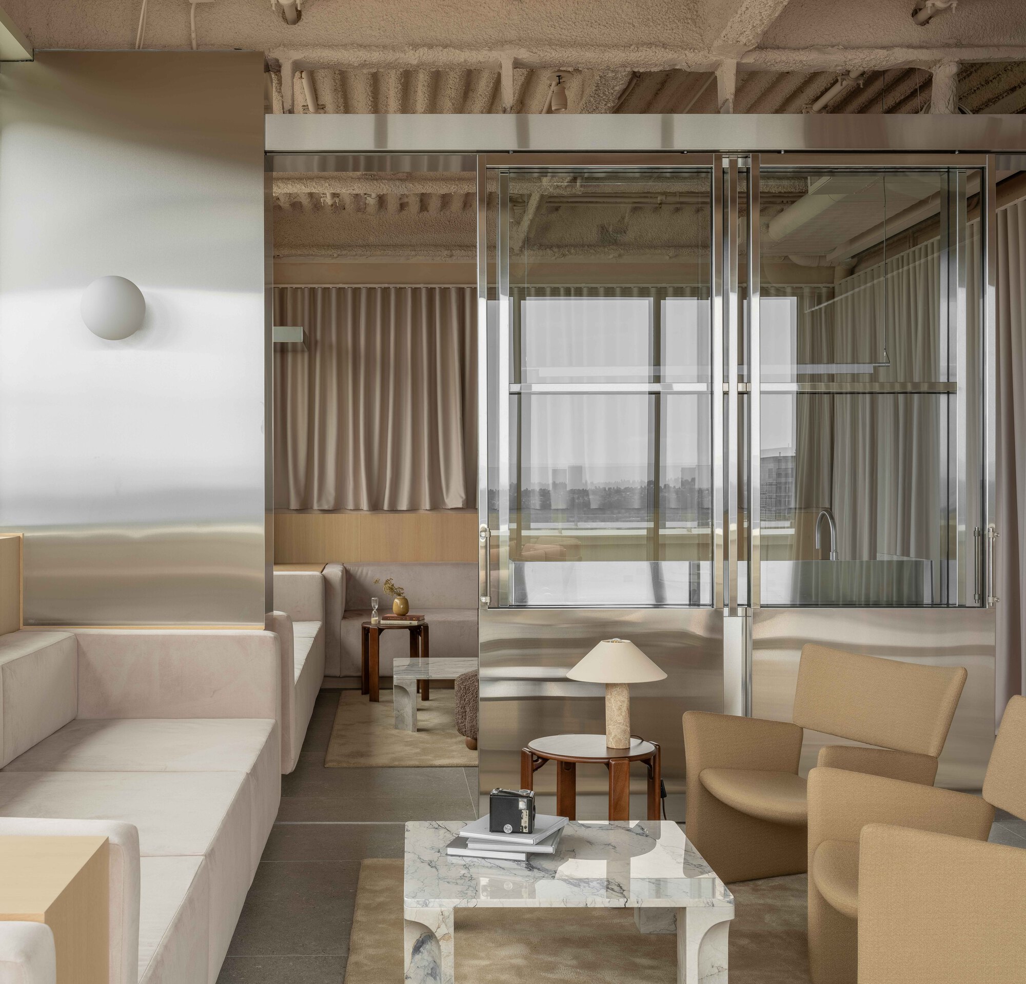 Interior lounge with exposed timber joists and steel framed glazing dividing adjacent spaces