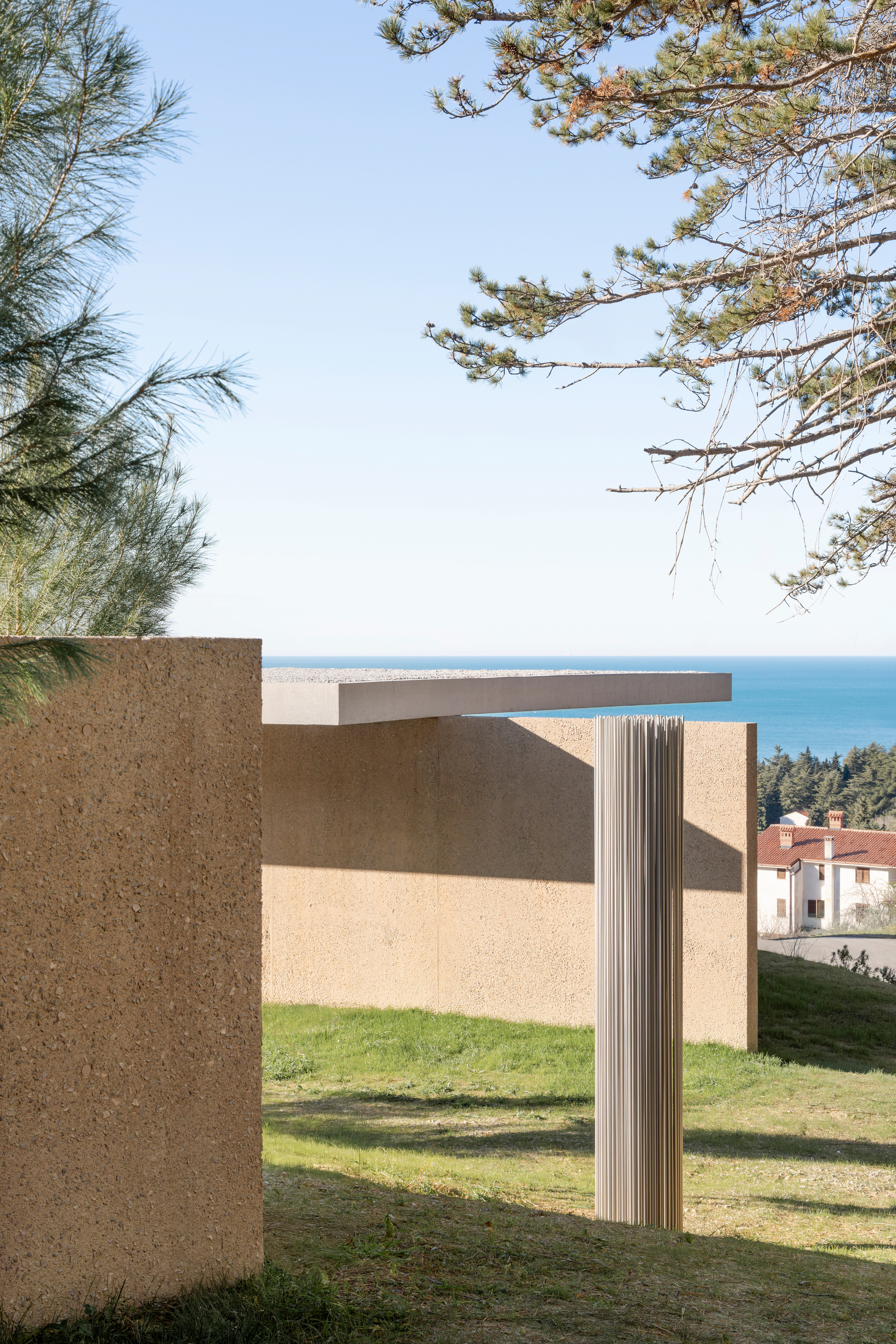 Fluted column detail between stucco walls with ocean views and pine branches overhead