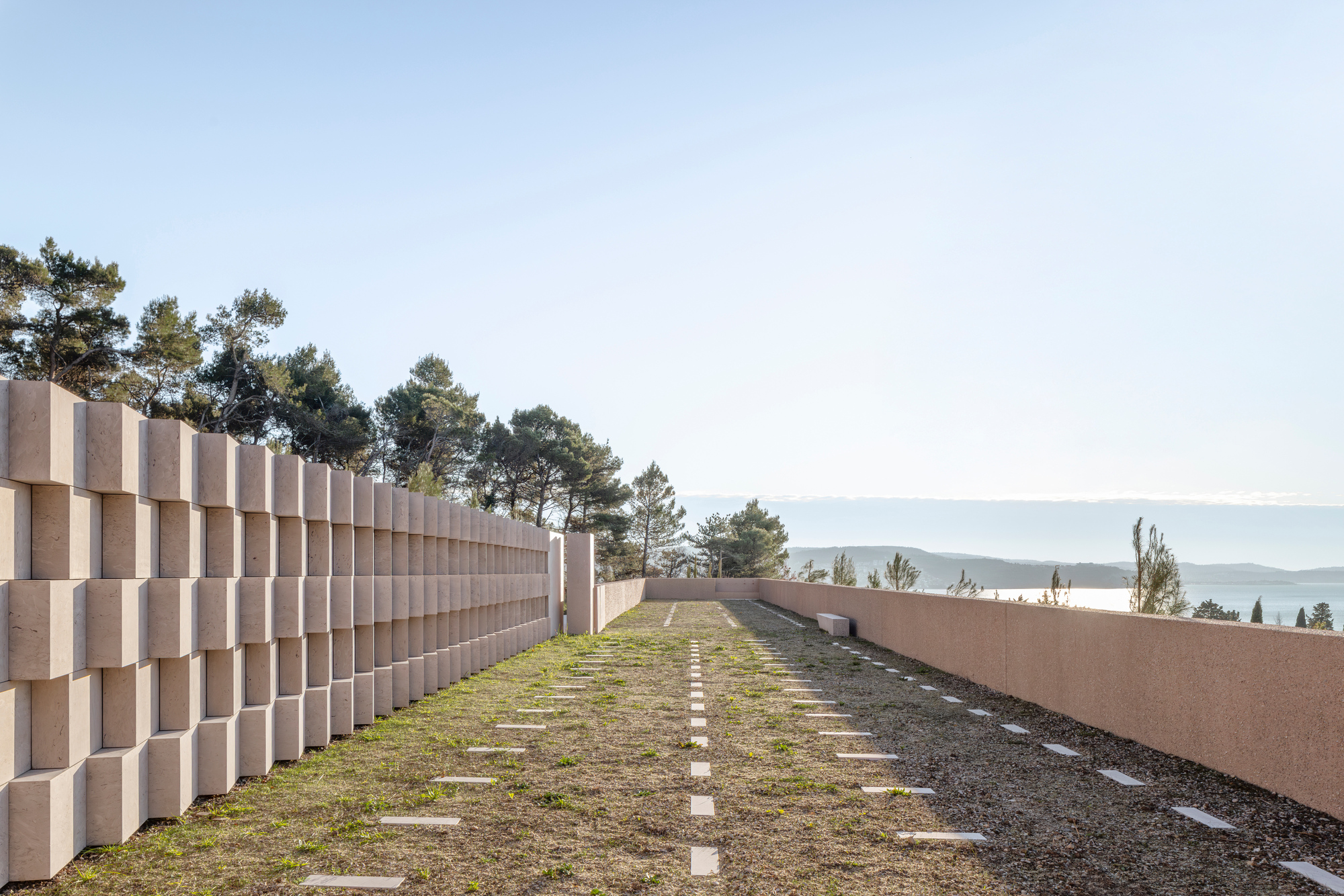 Green roof pathway between a stacked block wall and a cor-ten steel parapet overlooking distant water