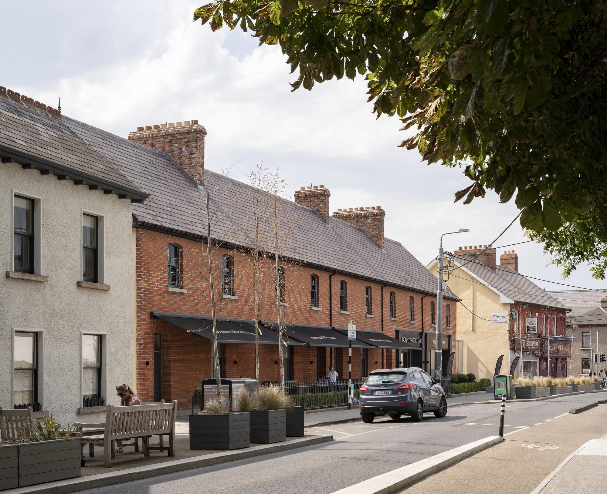Street view of red brick terraced housing with slate roofs and planters along the sidewalk