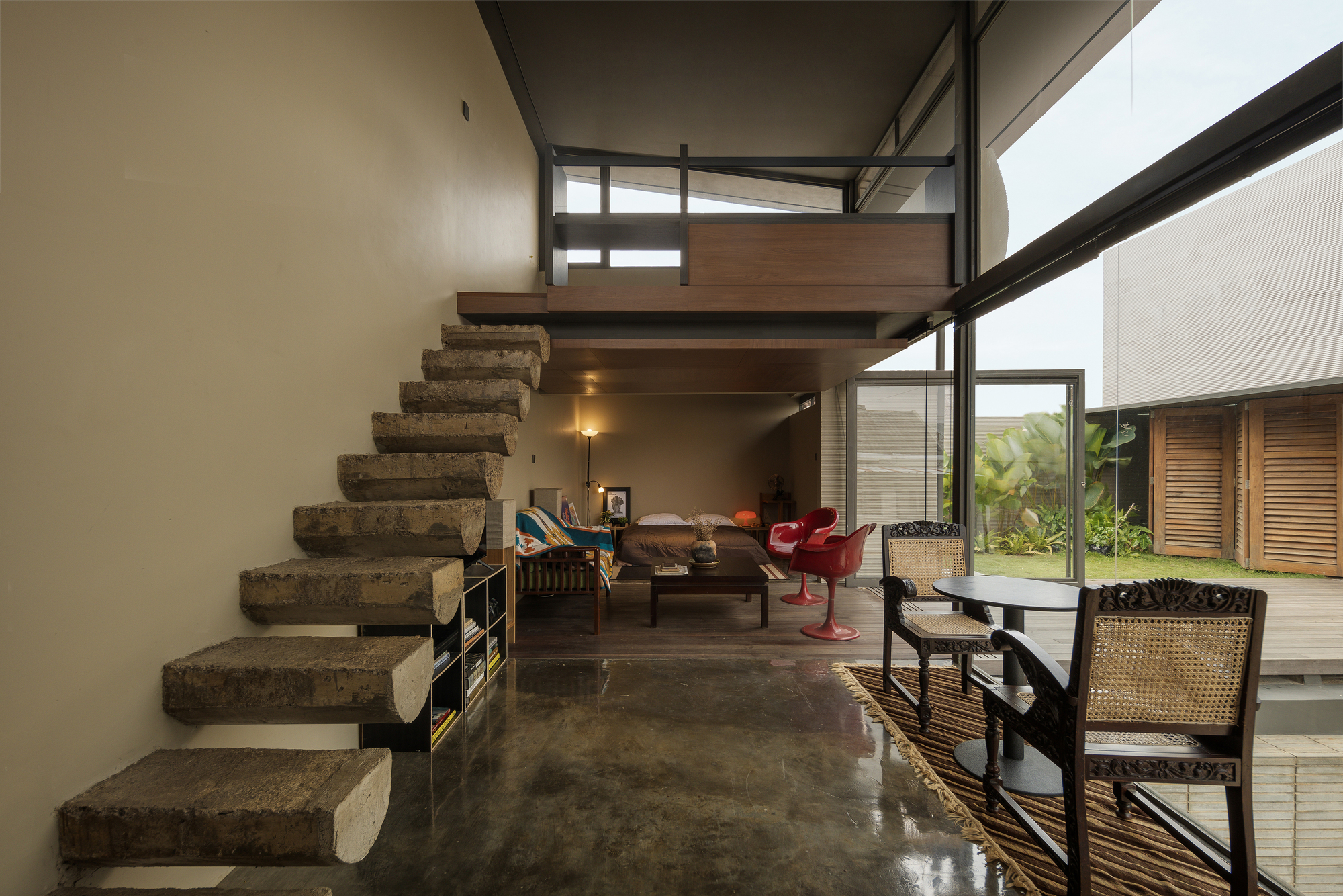 Interior living space with floating concrete staircase and double-height glazing overlooking the deck