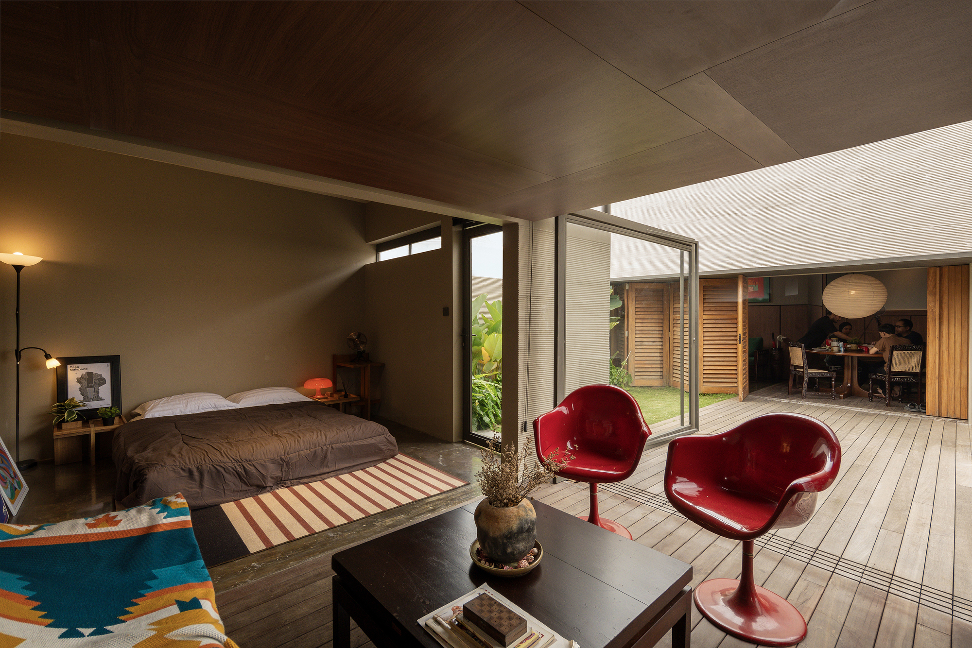 Bedroom opening onto timber deck with clerestory windows and slatted wood ceiling bathed in natural light