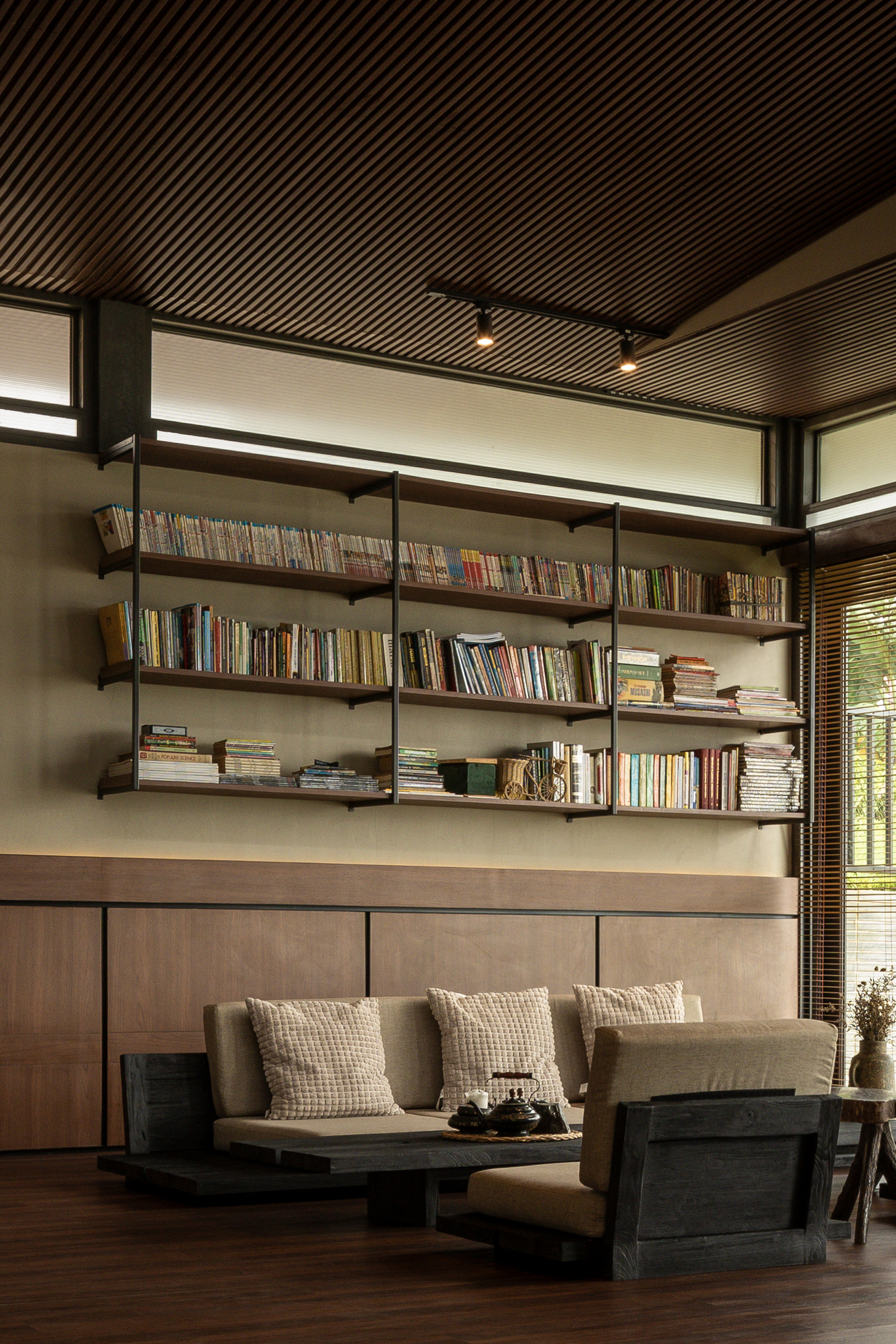 Built-in bookshelf beneath clerestory windows with timber slat ceiling and afternoon sunlight