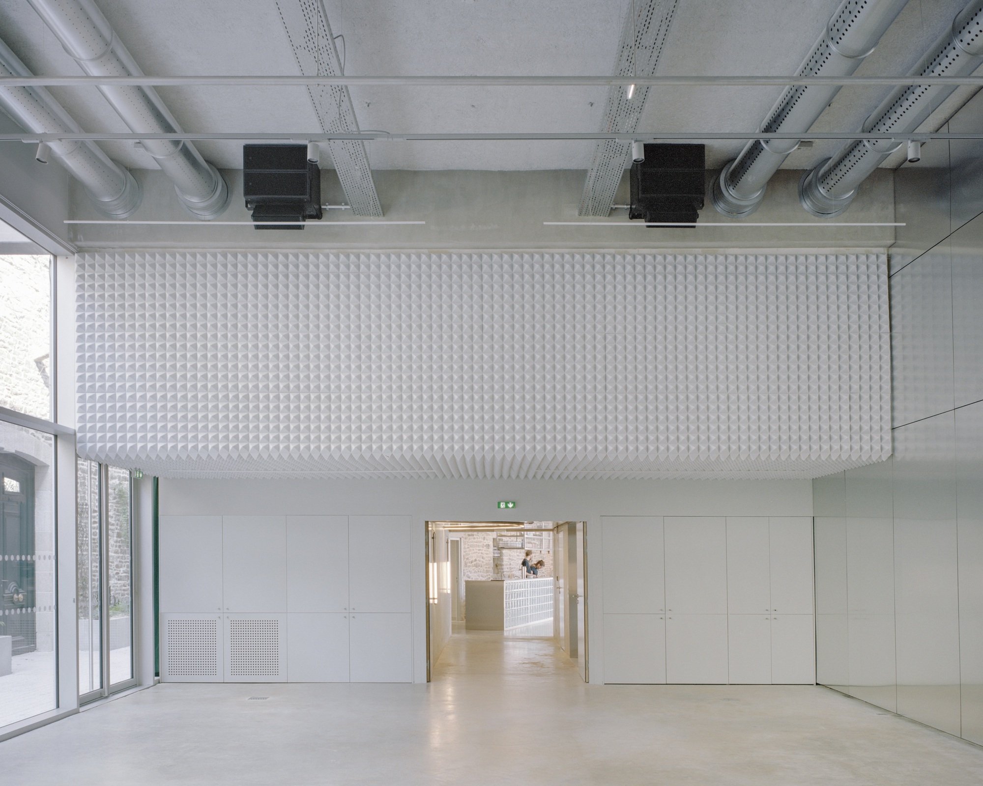Interior room with textured acoustic ceiling panel, exposed mechanical systems and polished concrete floor