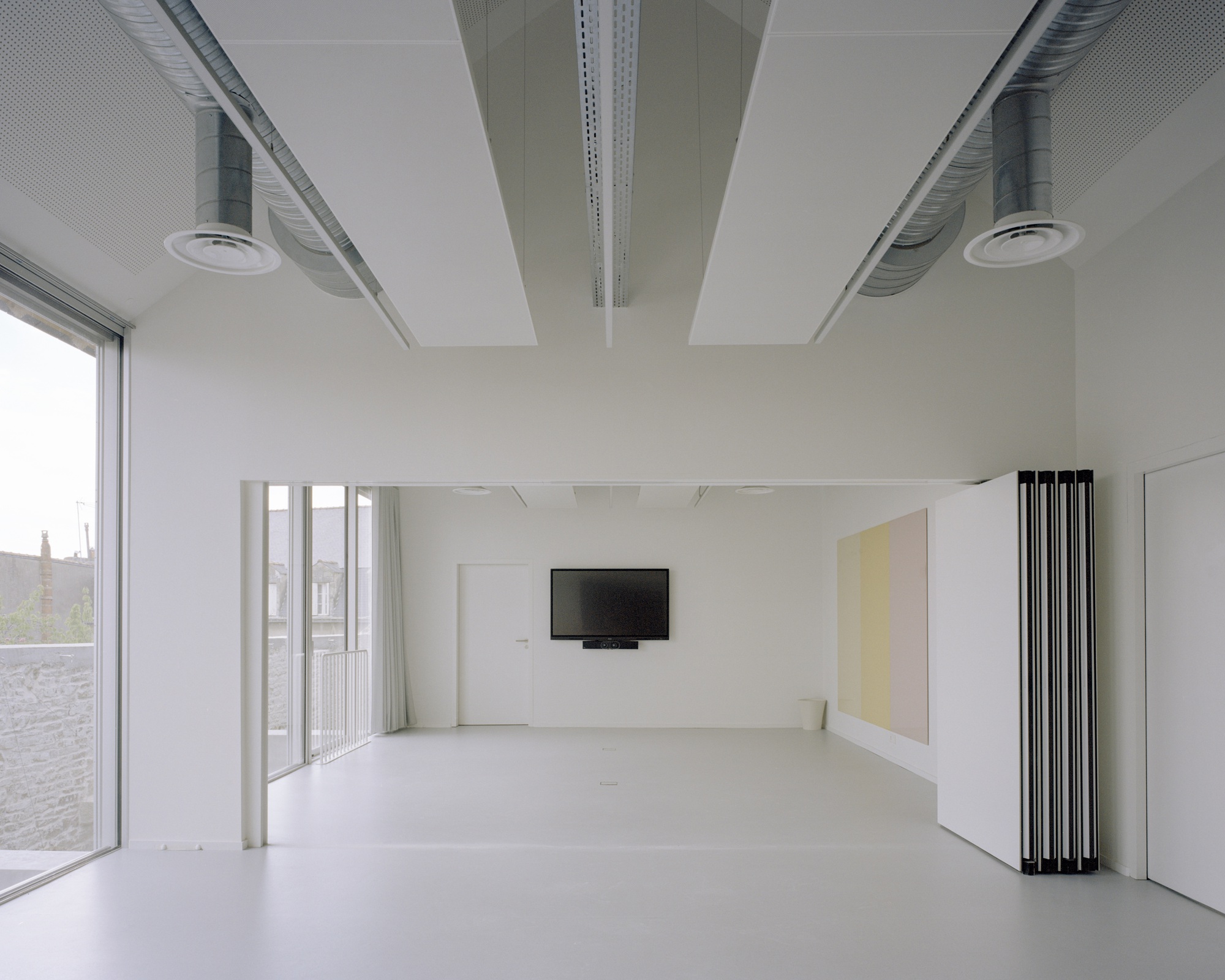 Interior space with retractable partition panels revealing a wall-mounted screen and folding furniture elements