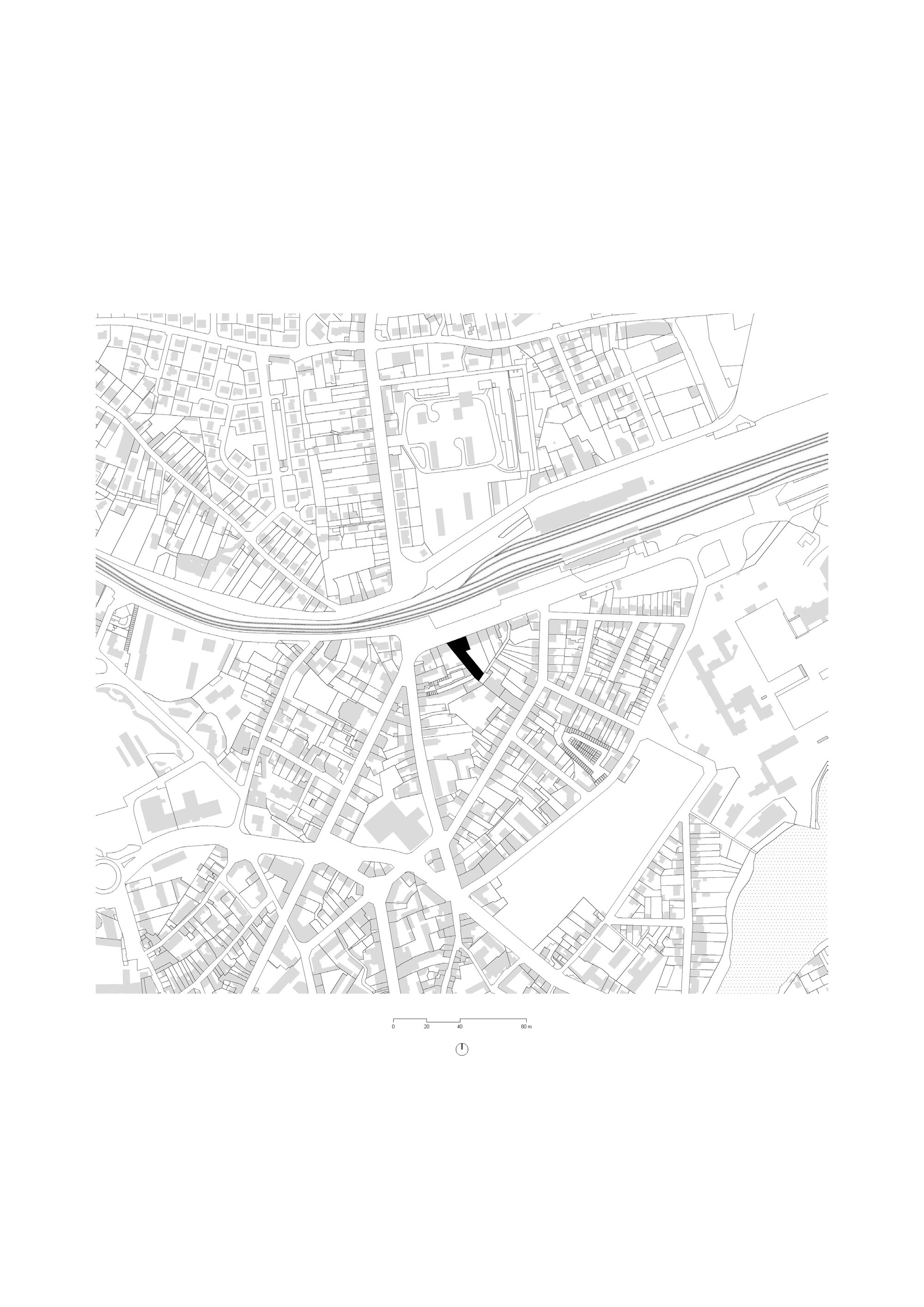 Site plan drawing showing building footprint highlighted in black within dense urban fabric and adjacent railway lines