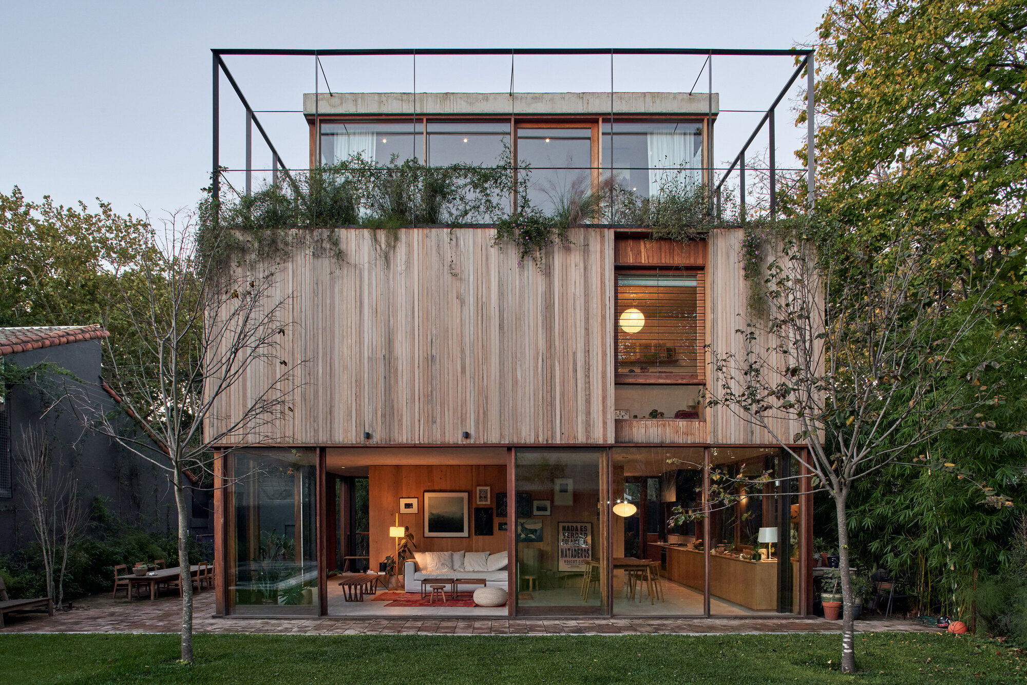 Garden facade with timber slatted upper volume, glazed ground floor opening to lawn and rooftop steel frame