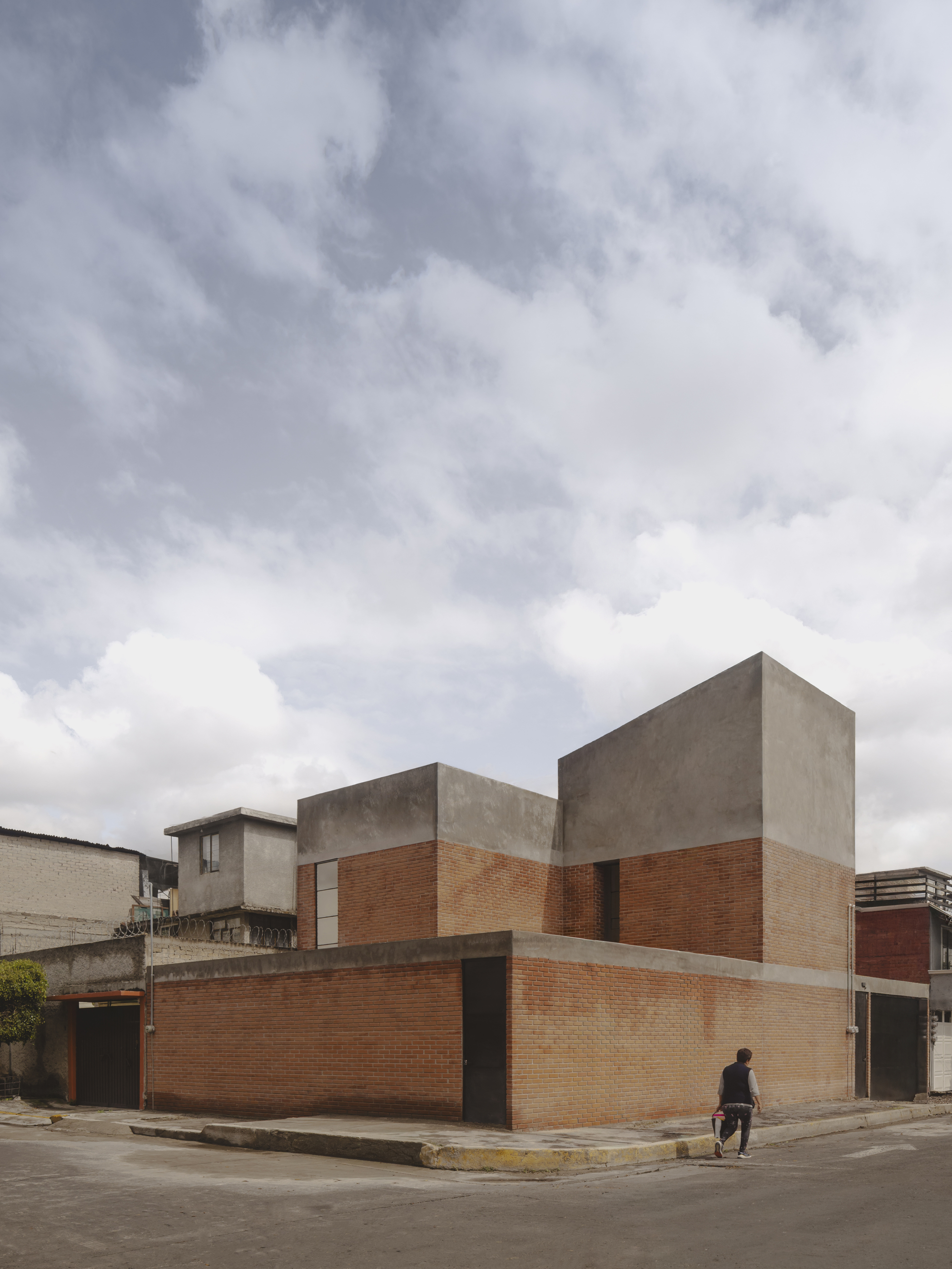 Corner view of the brick and concrete facade under an overcast sky with a pedestrian