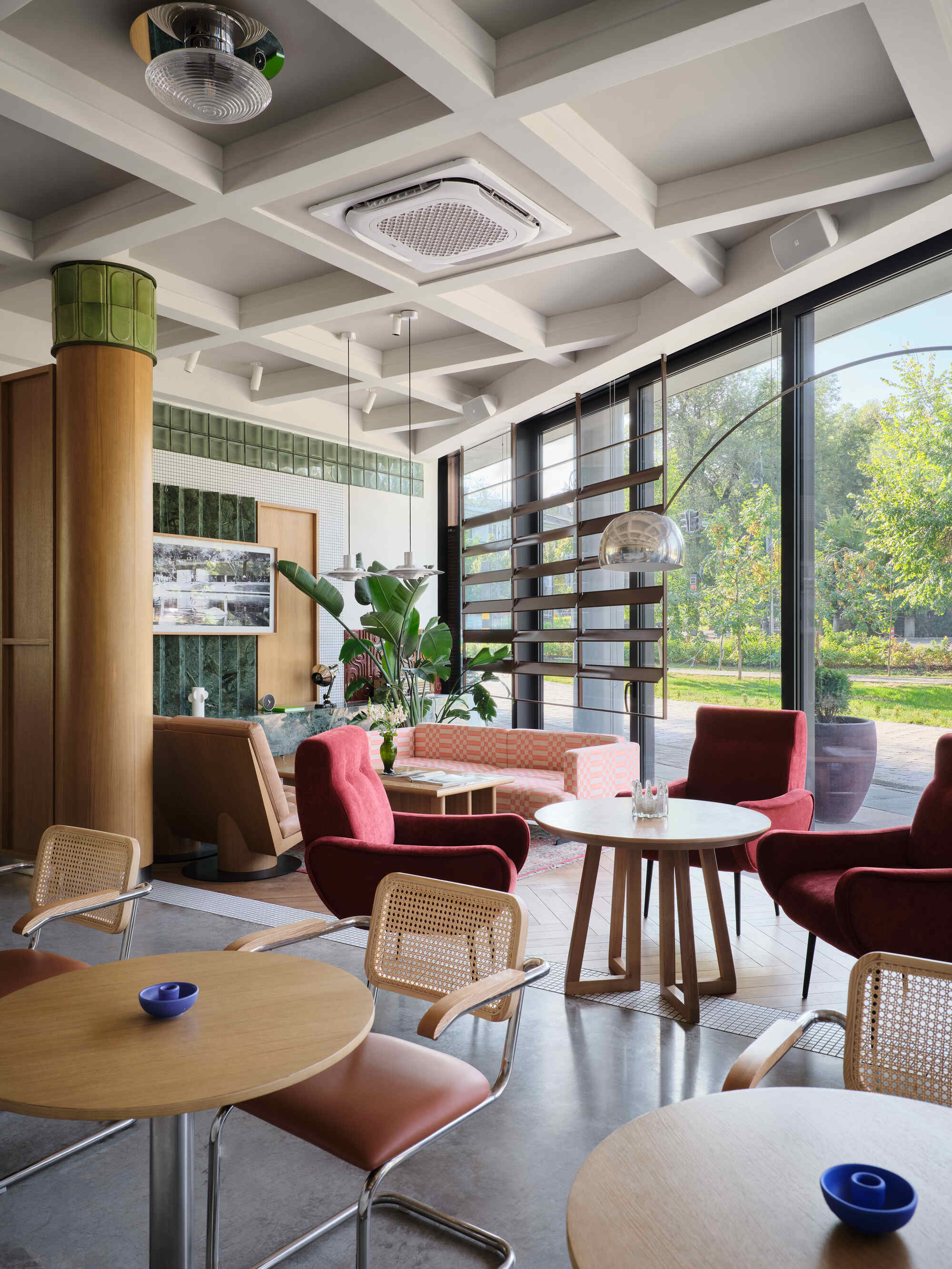 Dining area with coffered ceiling, floor-to-ceiling windows and green tiled column visible through daylight