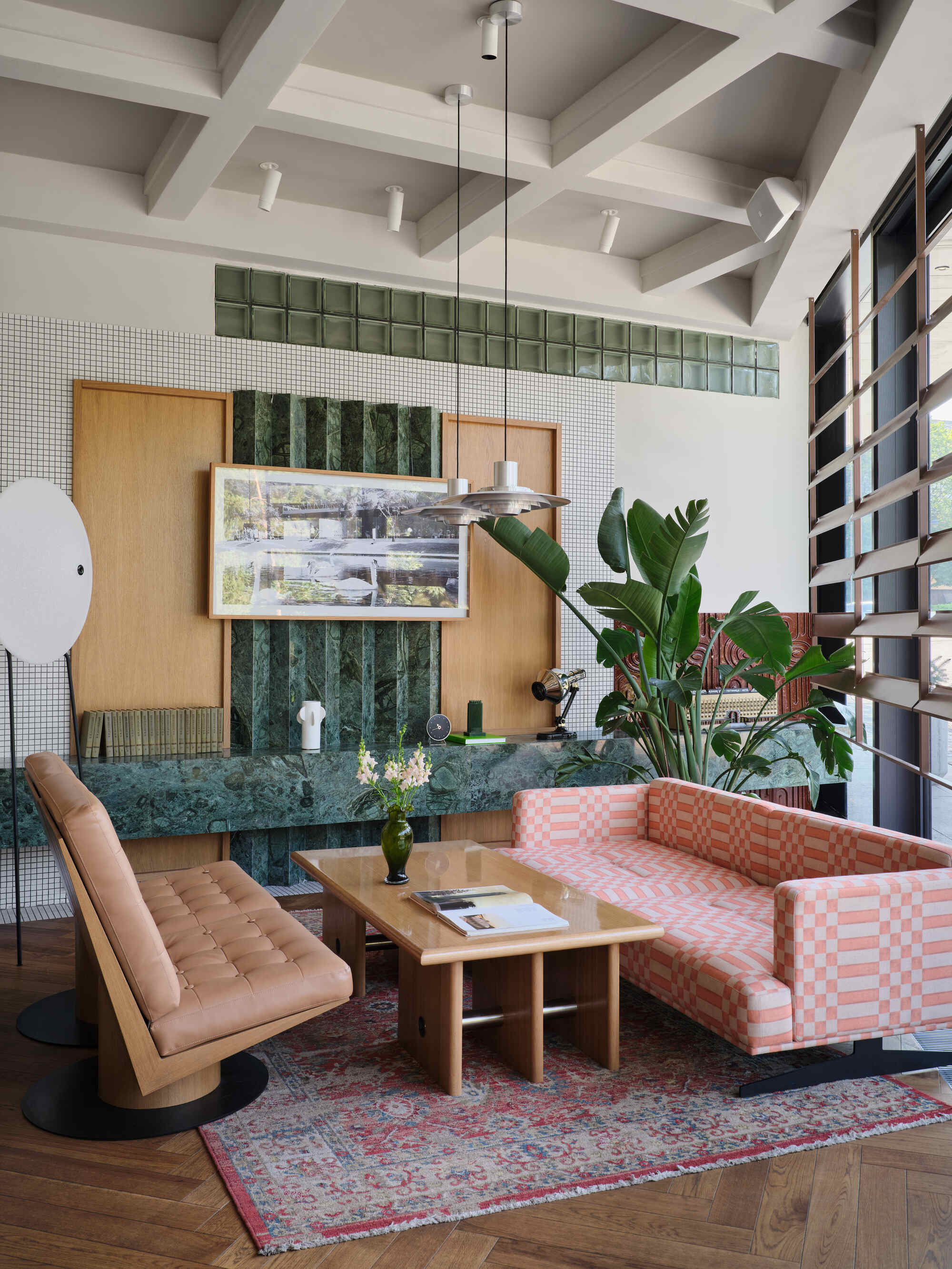 Lounge seating around green marble table with mosaic wall and timber cabinetry behind