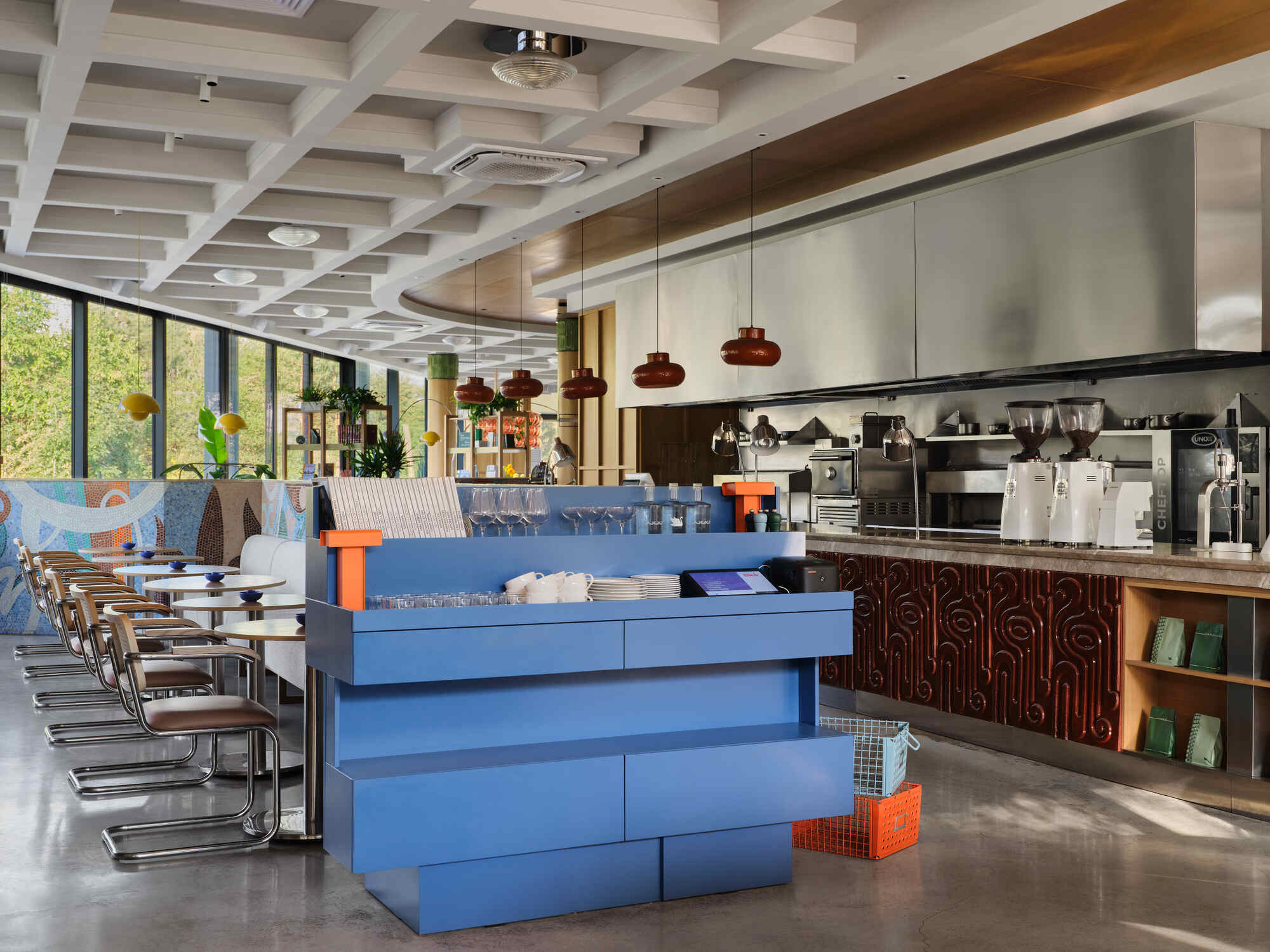 Coffee bar with blue laminate counter and pendant lights beneath a coffered ceiling with windows overlooking trees