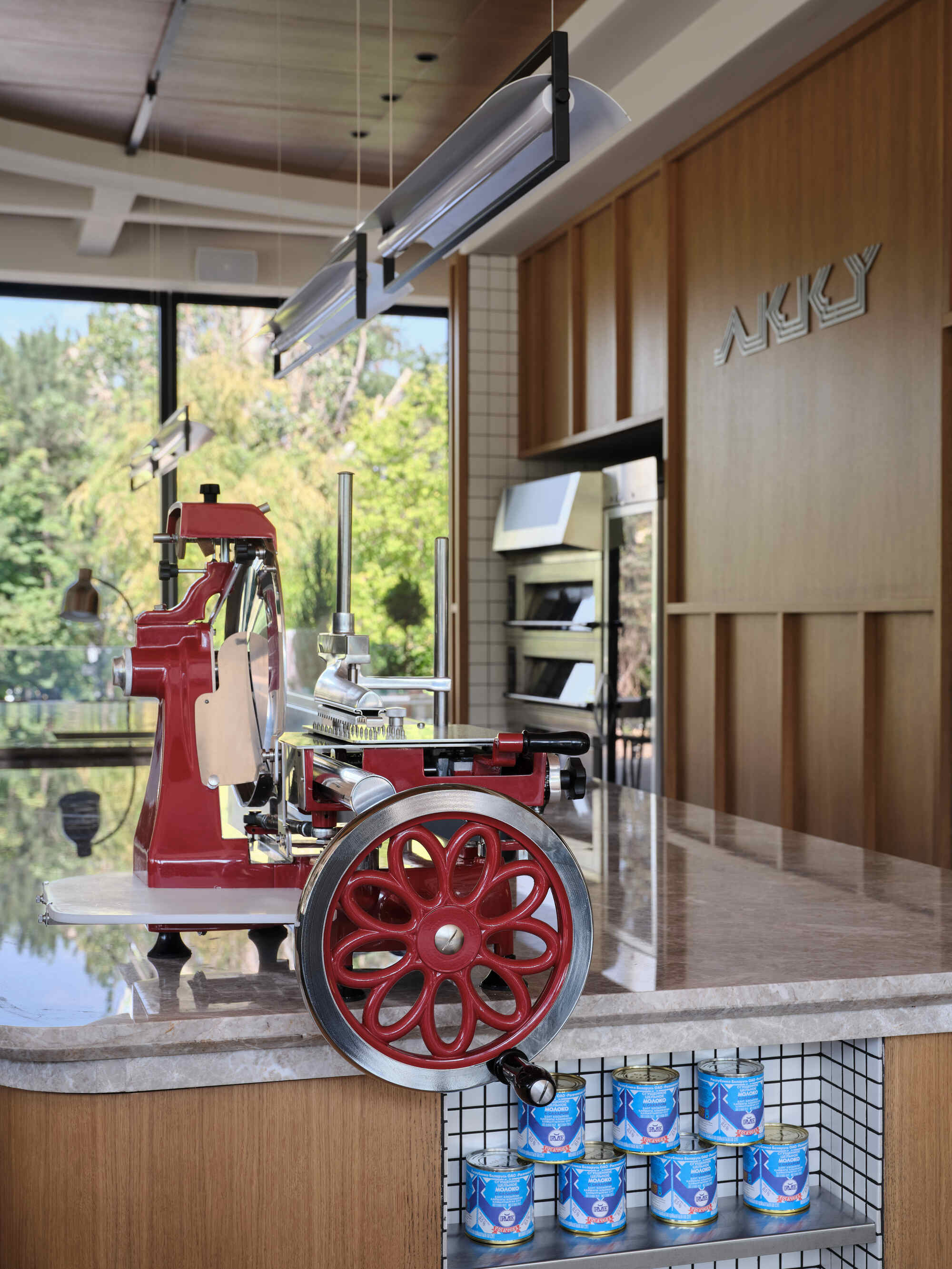 Red vintage espresso machine with spoked wheel on a marble counter near wood paneling and windows