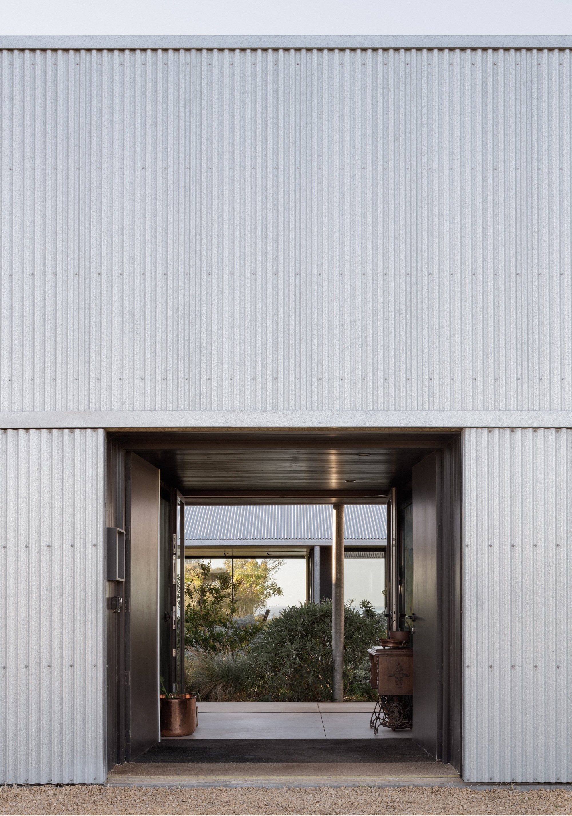Covered entry corridor framing a view through to a planted courtyard beyond