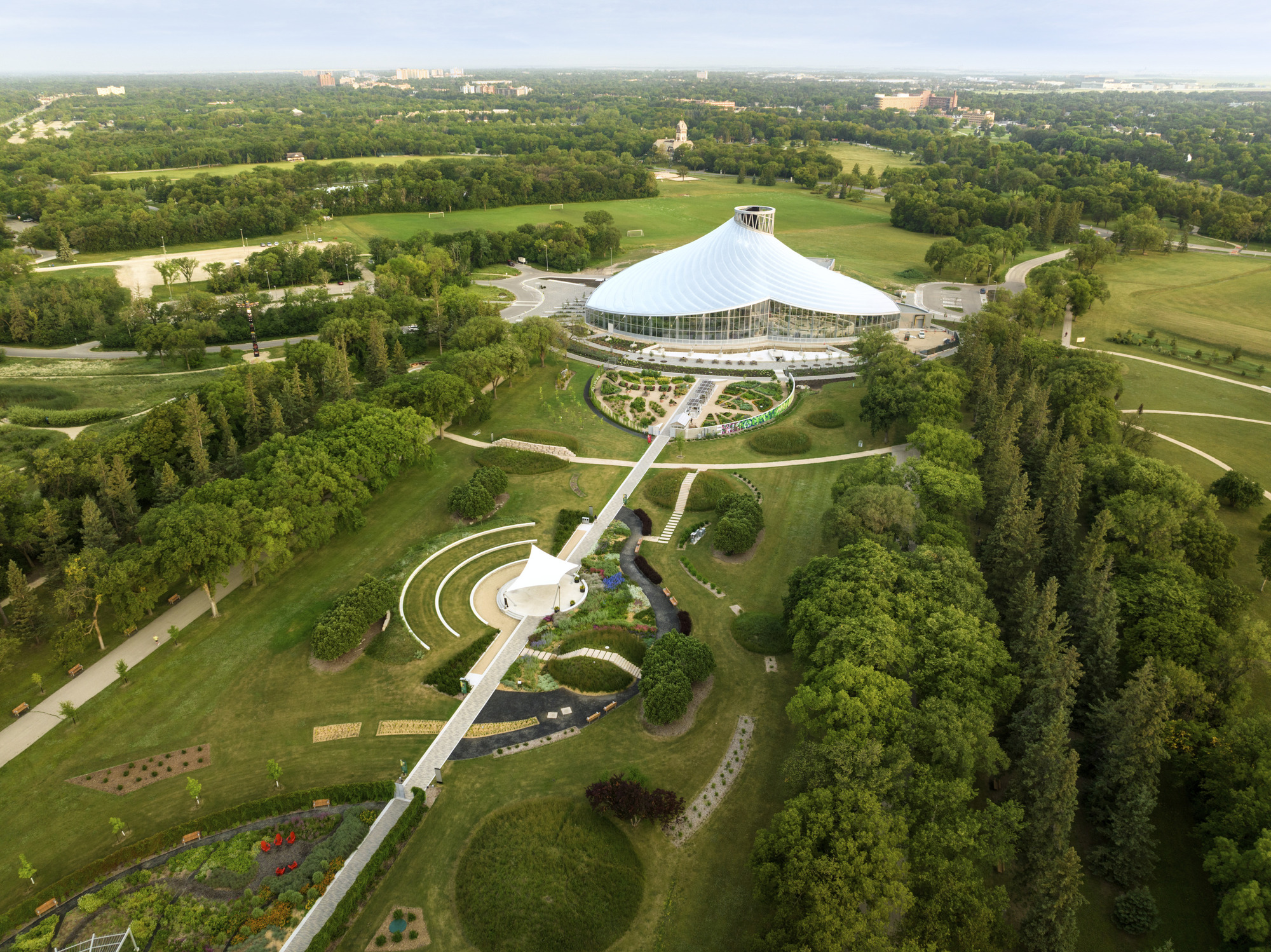 Aerial view of the conical glass conservatory within curved garden paths surrounded by parkland and forest