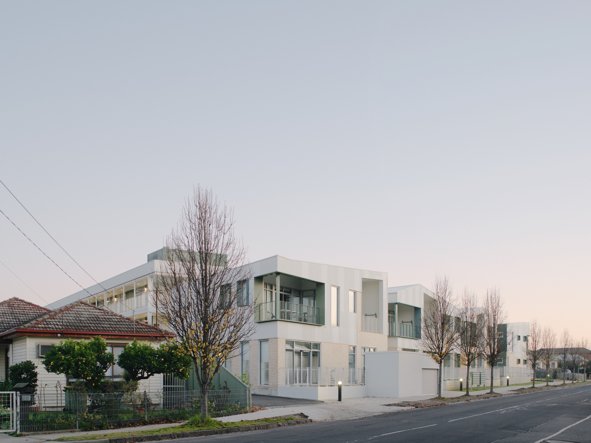 Row of attached dwellings with arched openings and balconies at dusk