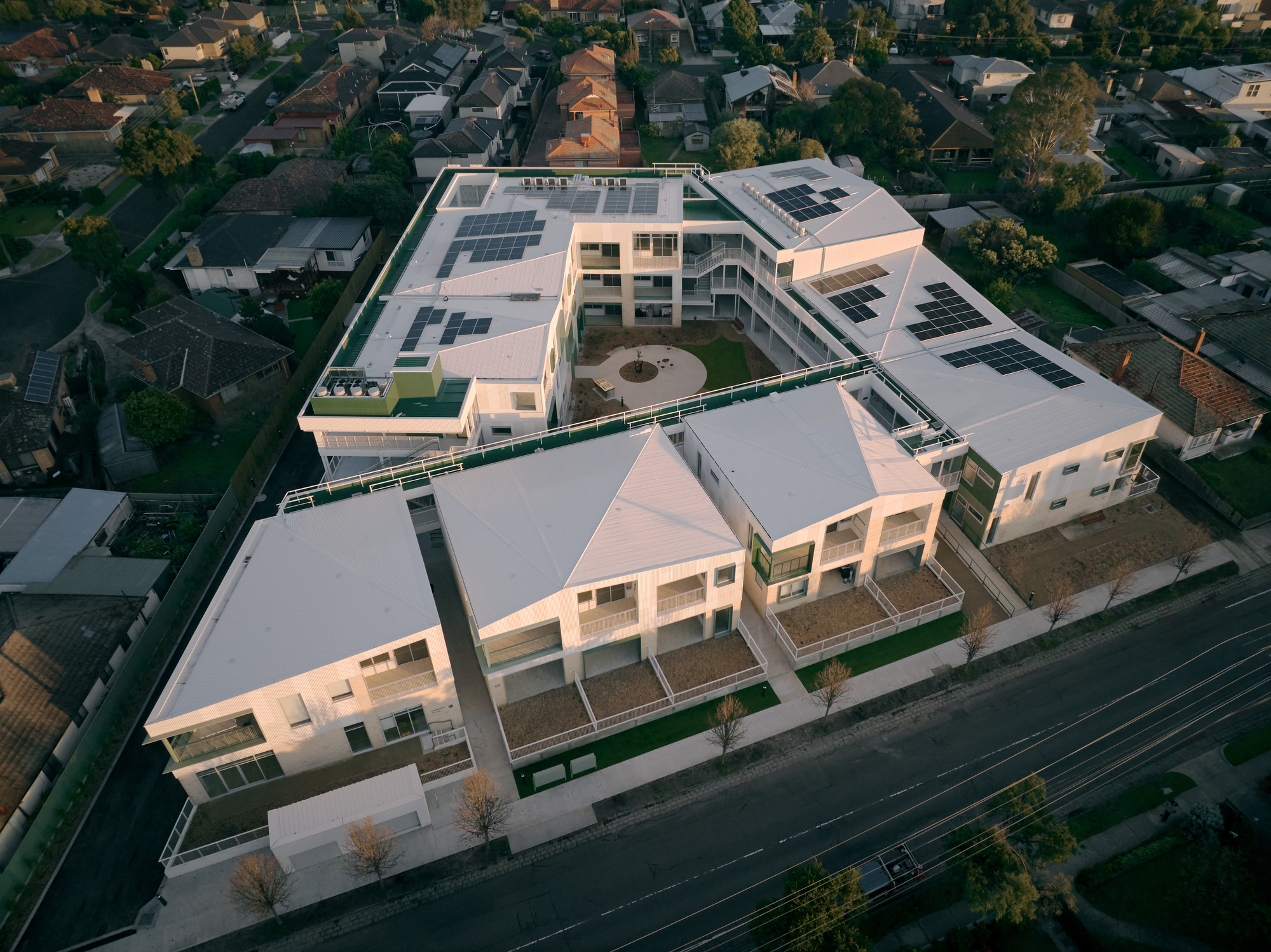 Aerial view of courtyard housing complex with photovoltaic panels on roofs