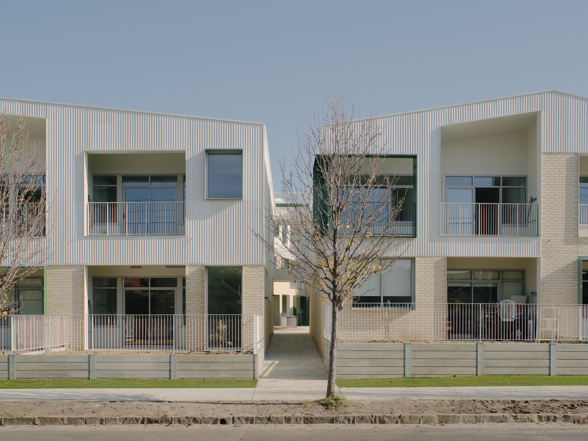 Frontal view showing the central passageway flanked by units with brick base and ribbed upper cladding