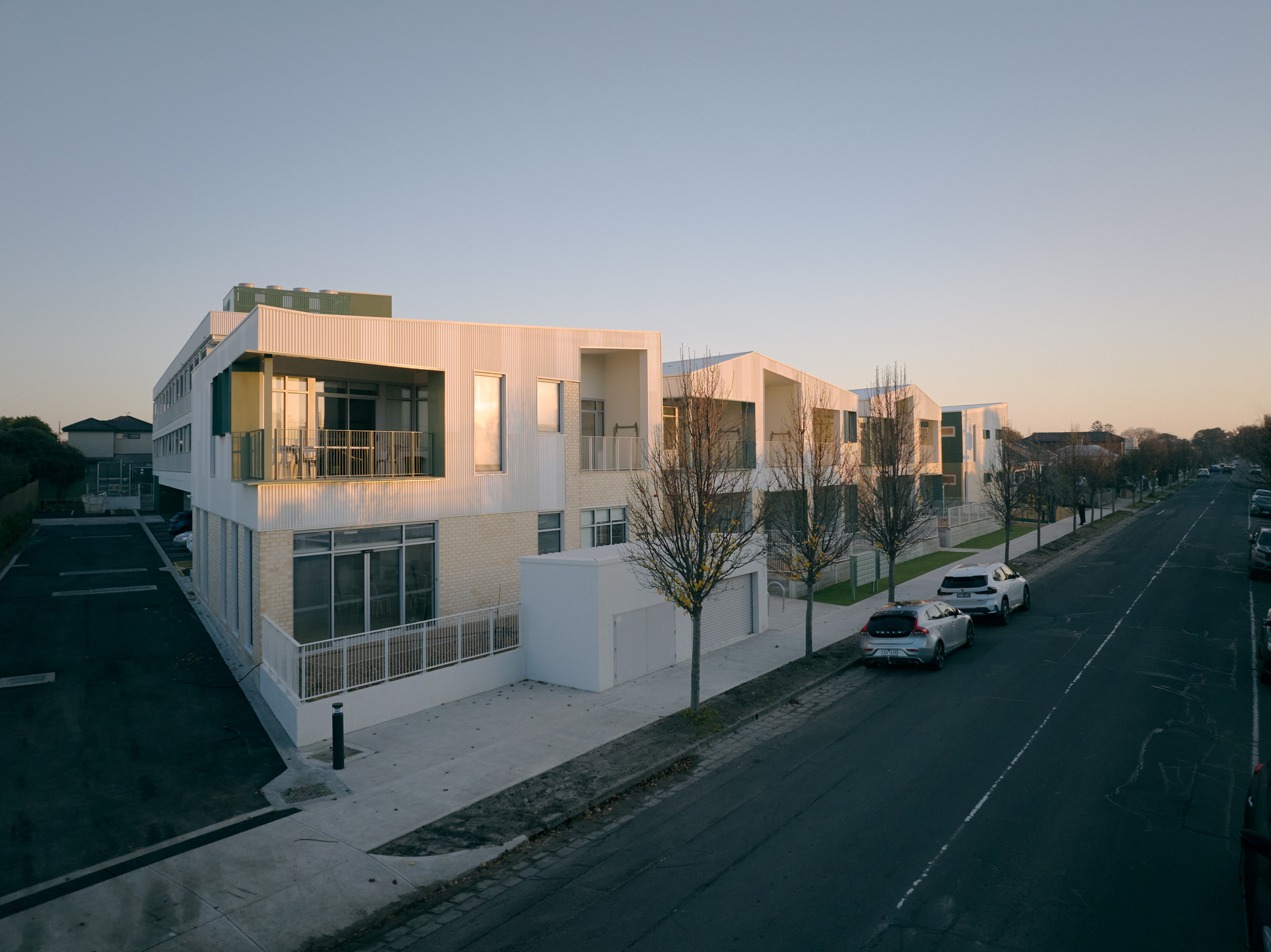 Elevated view of the residential street at dusk with parked cars and young street trees