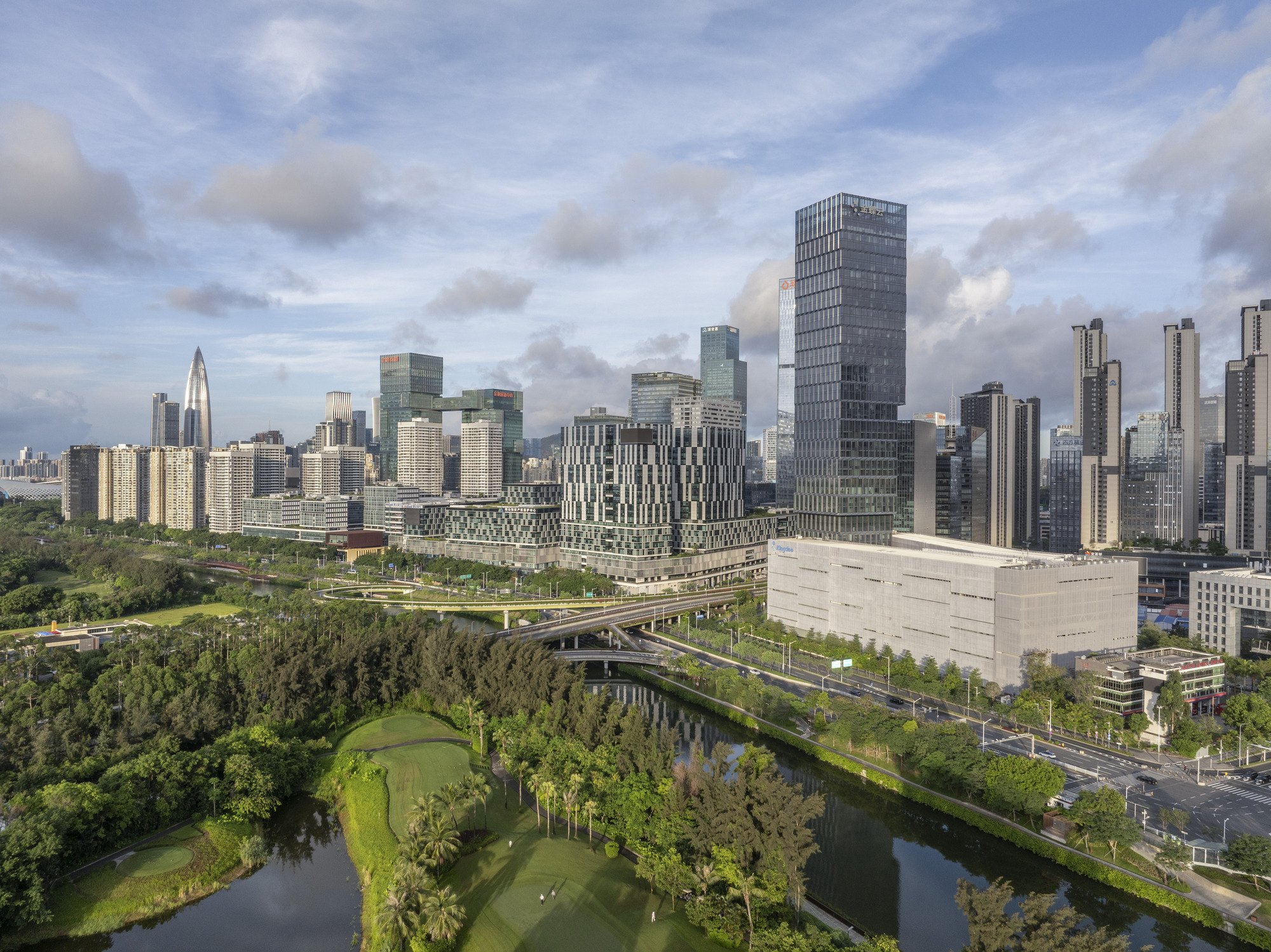 Aerial view of tower cluster beside elevated highway threading through park and waterway
