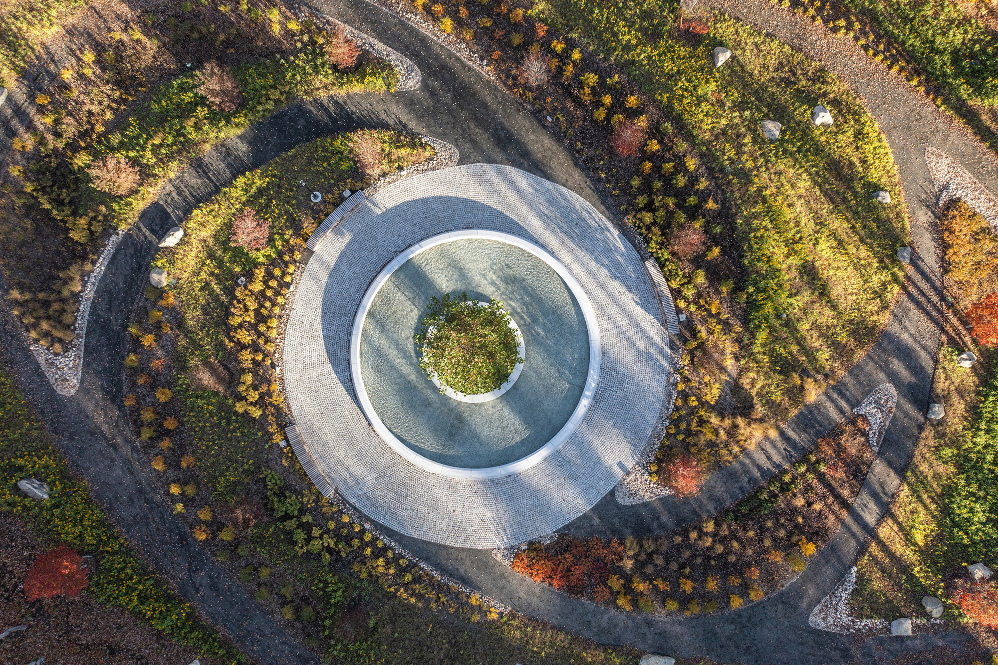 Aerial view of the circular water feature with central island and radiating landscape beds in fall