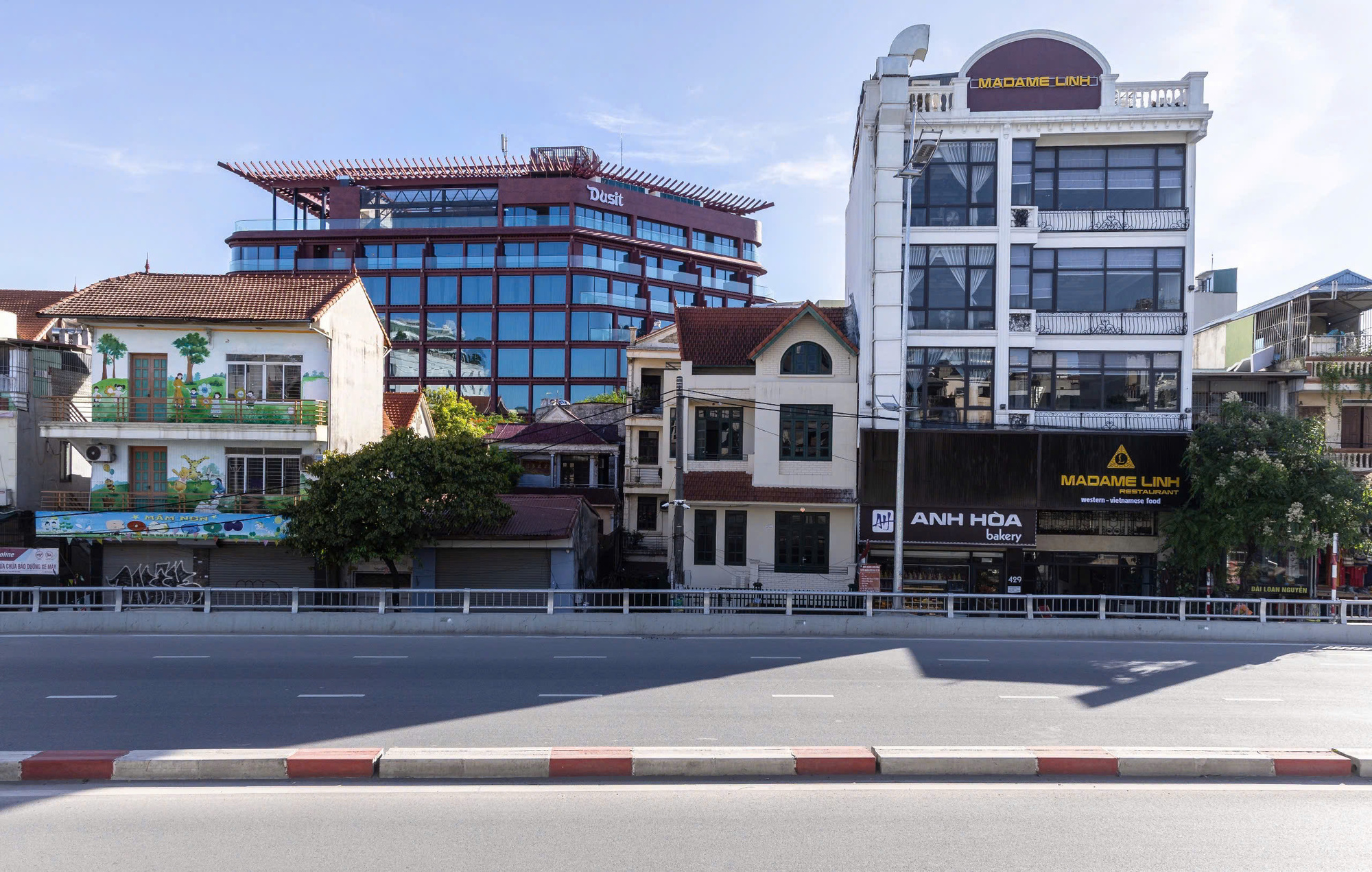 Street elevation showing the red louvered volume rising behind existing low-rise buildings along the roadway