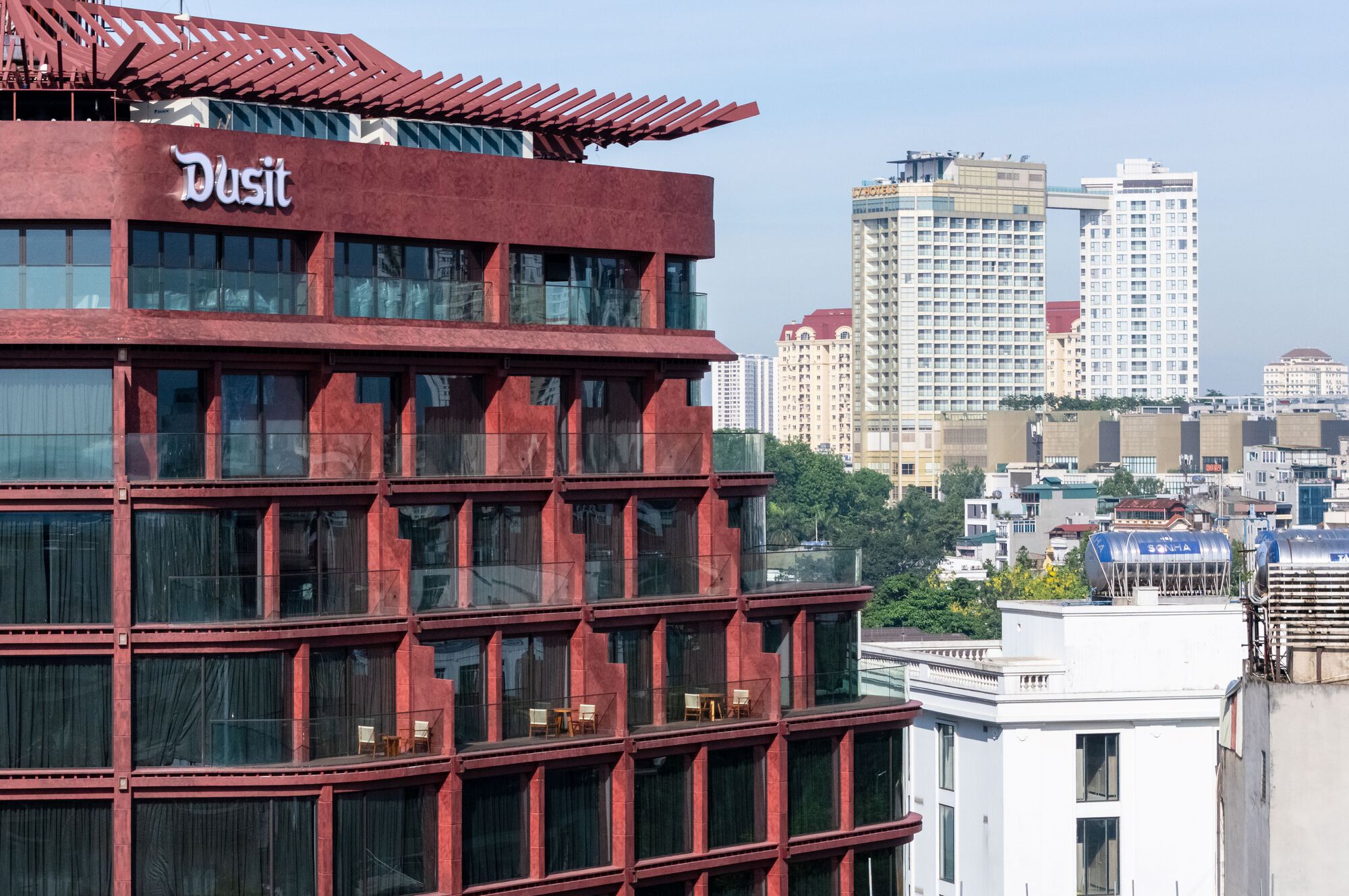 Corner facade with red structural frame and recessed glass panels viewed against neighboring towers